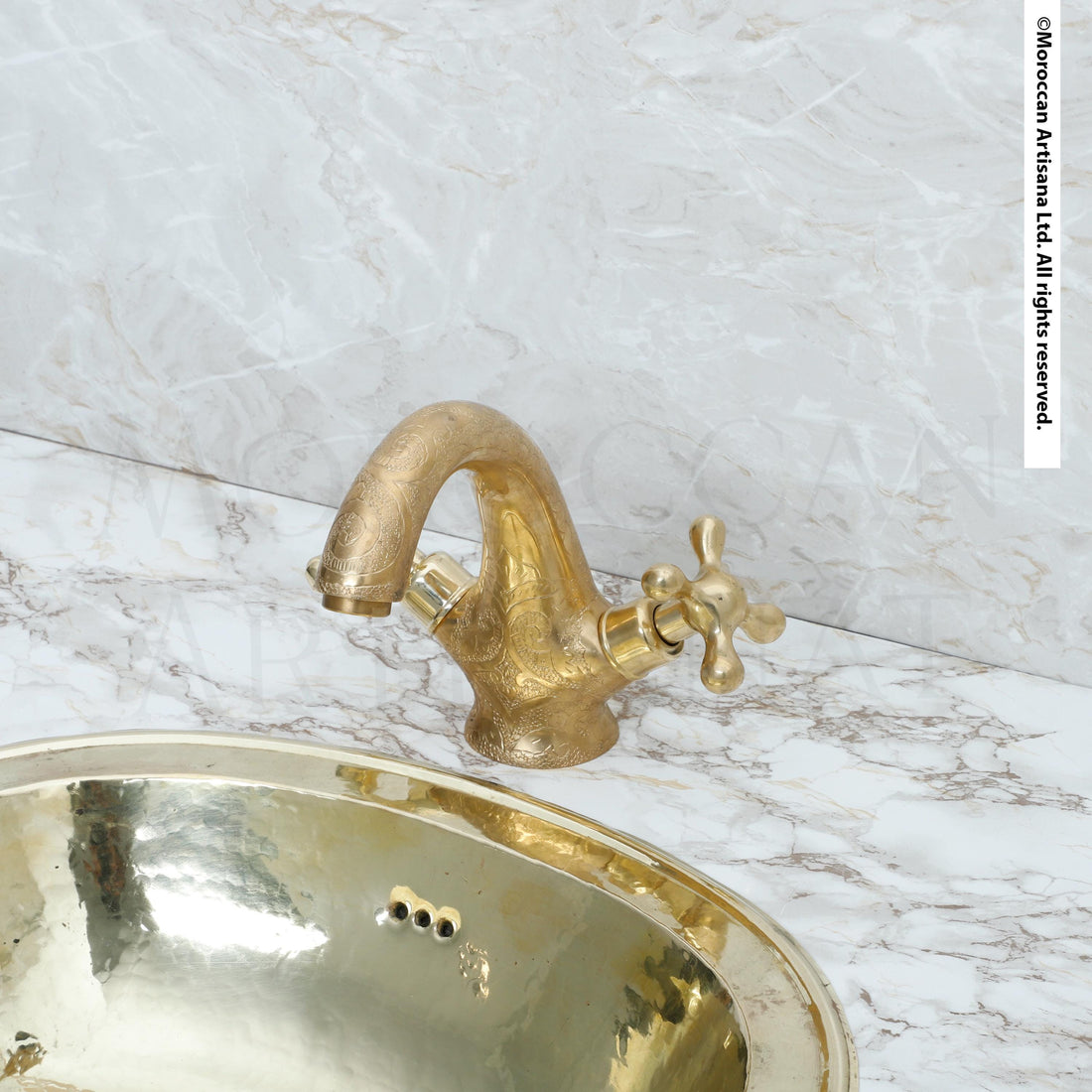 a gold-colored bathroom sink with a brass faucet, set against a marble countertop.