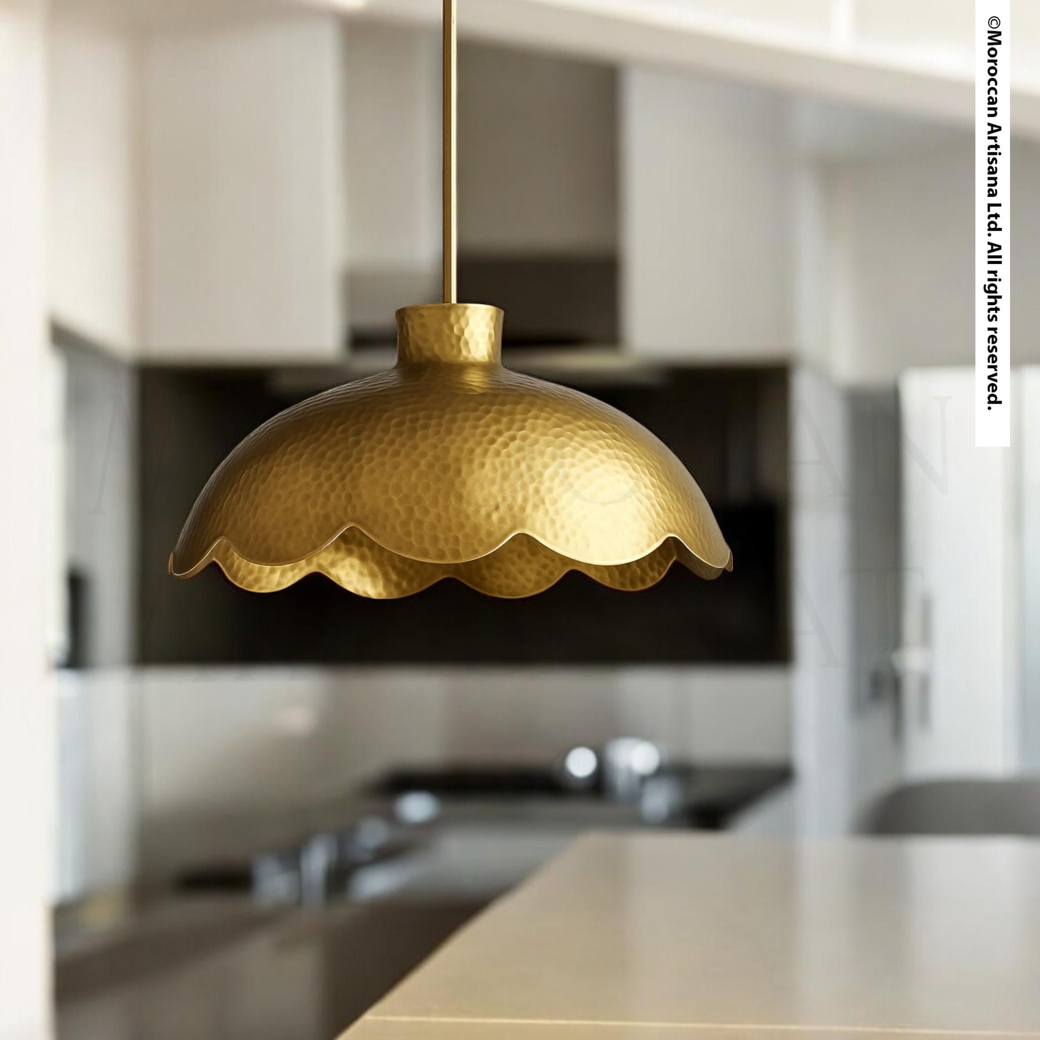 A gold-colored pendant light hangs from the ceiling in a modern kitchen, casting a warm glow over the space.
