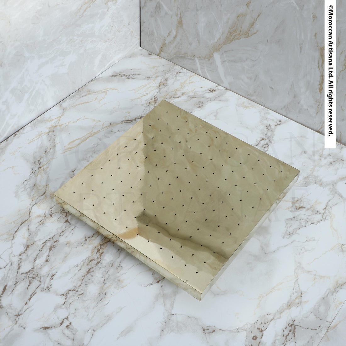 a square, metallic surface with a grid-like pattern of small holes or dots on it, placed on a marble countertop or floor.