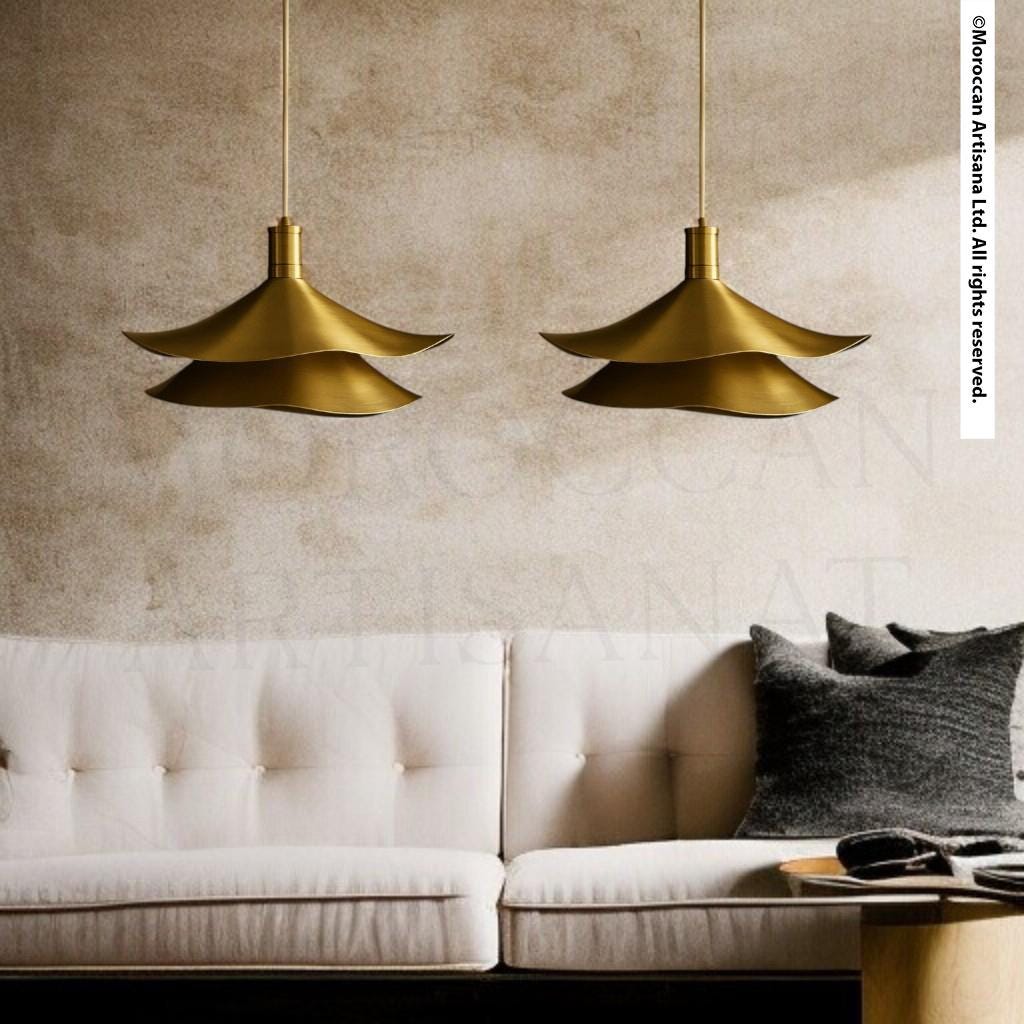 a modern living room with a white sofa and two gold pendant lights hanging above it.