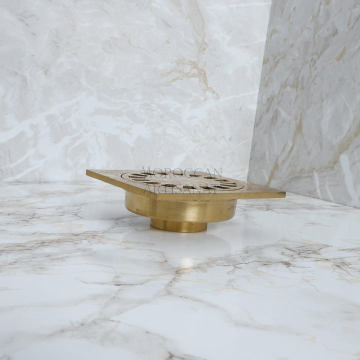 Brass drain cover on a marble floor with 'Napoleon' branding.