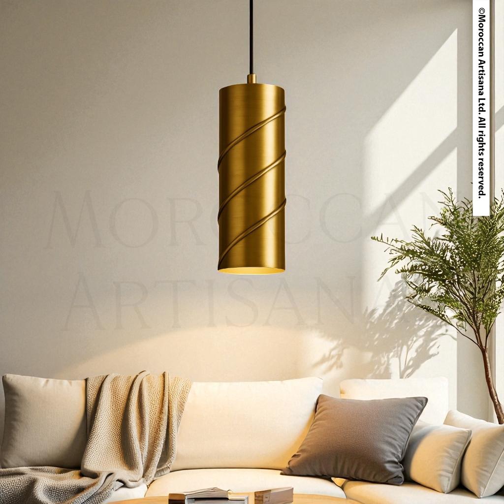 a modern living room with a gold-colored cylindrical pendant light hanging from the ceiling, casting a warm glow over the white sofa and a plant in the corner.