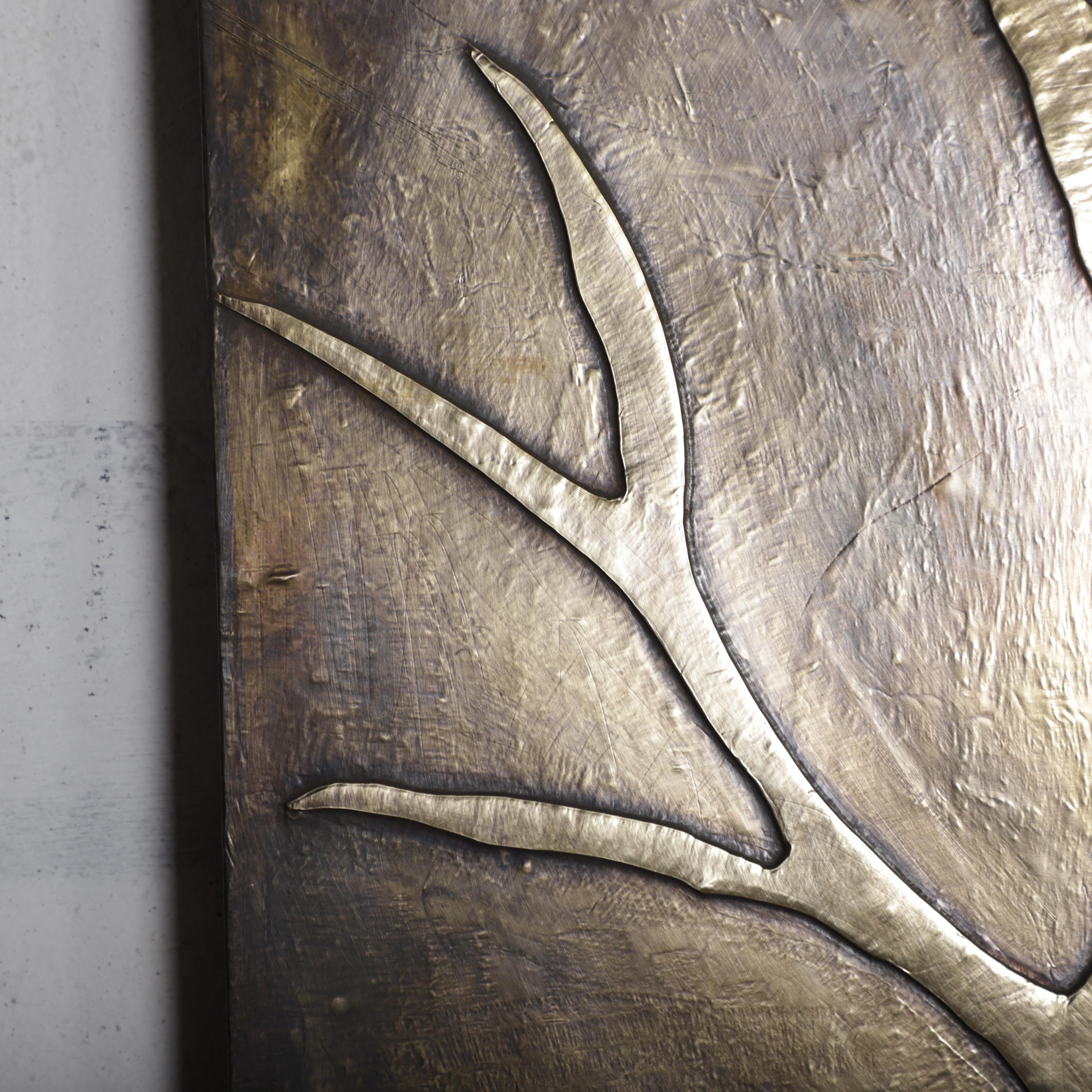 a close-up view of a textured surface with a metallic, bronze-like appearance. The surface appears to be a piece of wall art or a decorative element, with a distinct pattern or design that draws the viewer&#39;s attention.