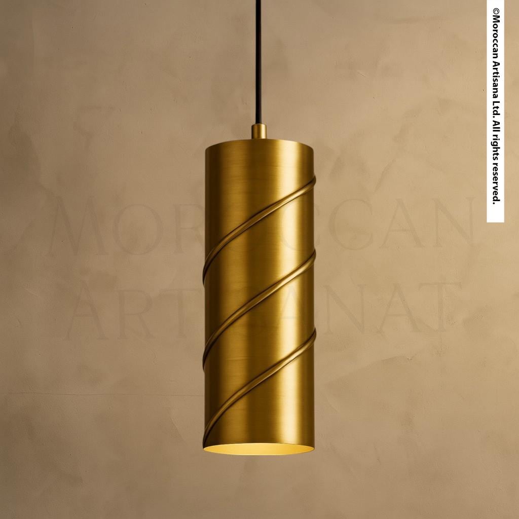 A gold-colored cylindrical pendant light with a curved design hangs from a black cord against a beige background.