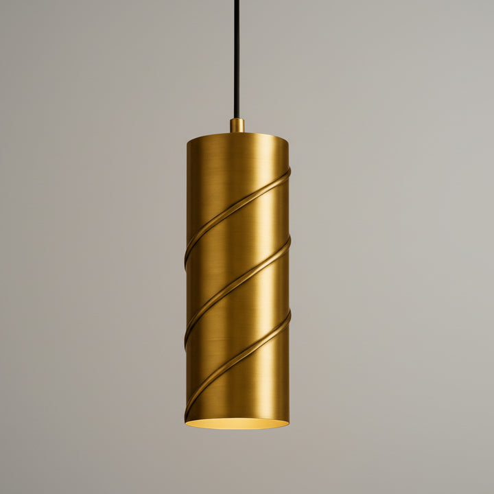 A gold-colored cylindrical pendant light with a curved design hangs from a black cord against a beige background.