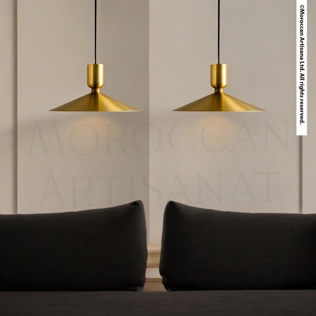two gold pendant lights hanging from the ceiling, casting a warm glow over a black couch in the foreground.