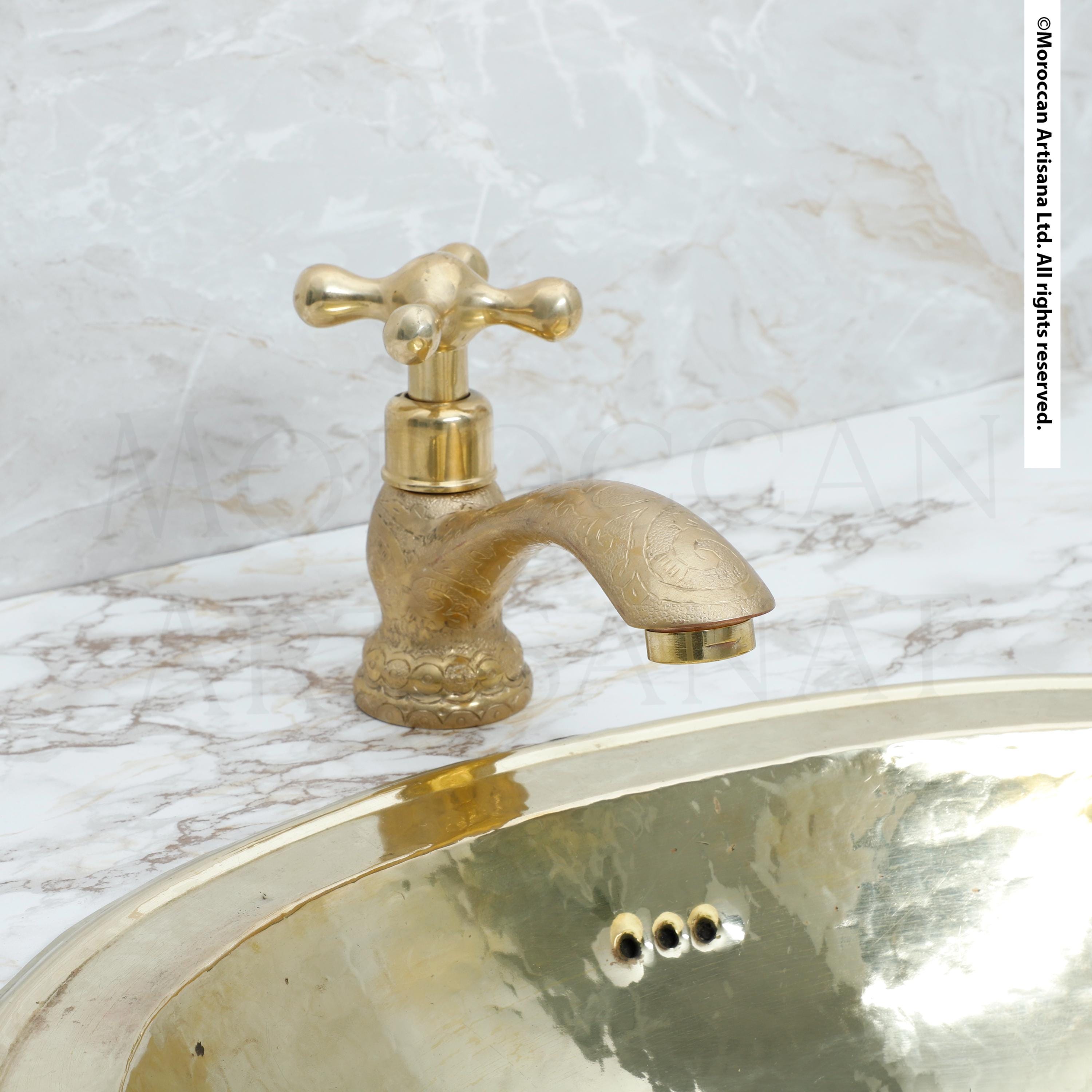 a gold-colored faucet and a marble sink, both of which appear to be made of brass or gold.