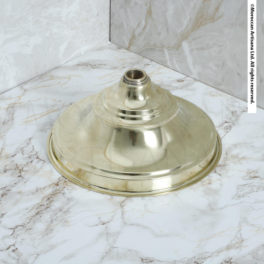 A brass-colored lamp base is placed on a marble countertop.