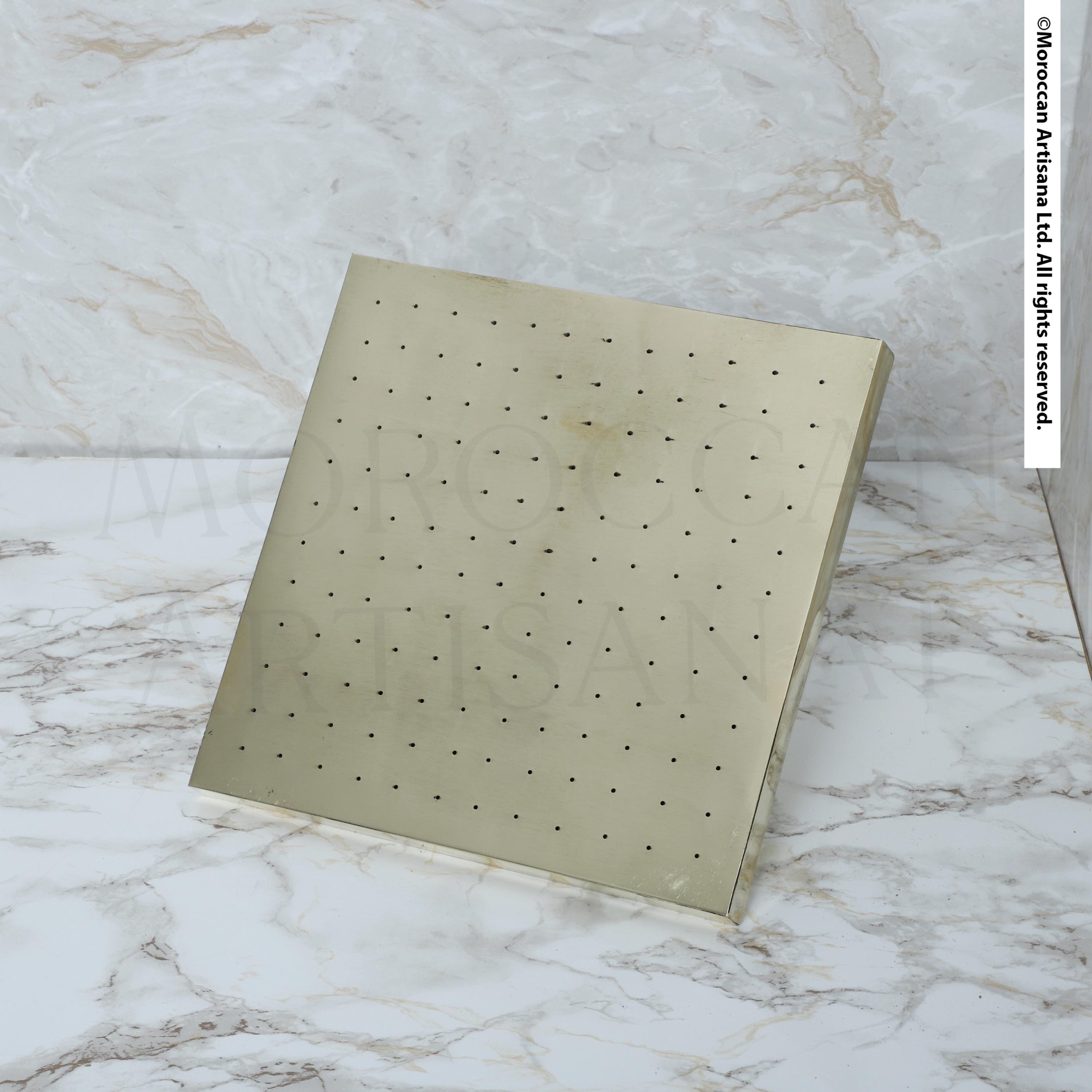 a square-shaped, metallic object with a grid-like pattern on its surface, placed on a marble countertop.