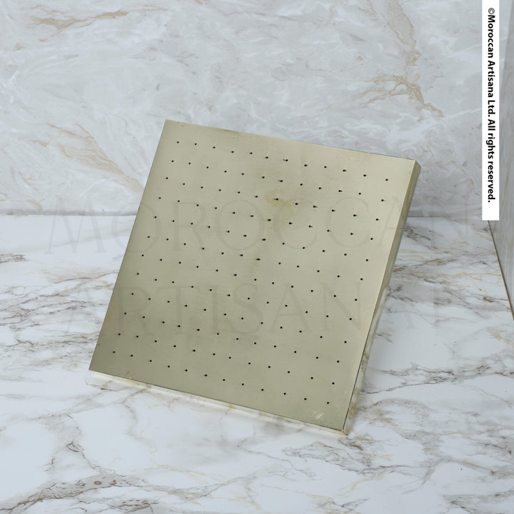 a square-shaped, metallic object with a grid-like pattern on its surface, placed on a marble countertop.