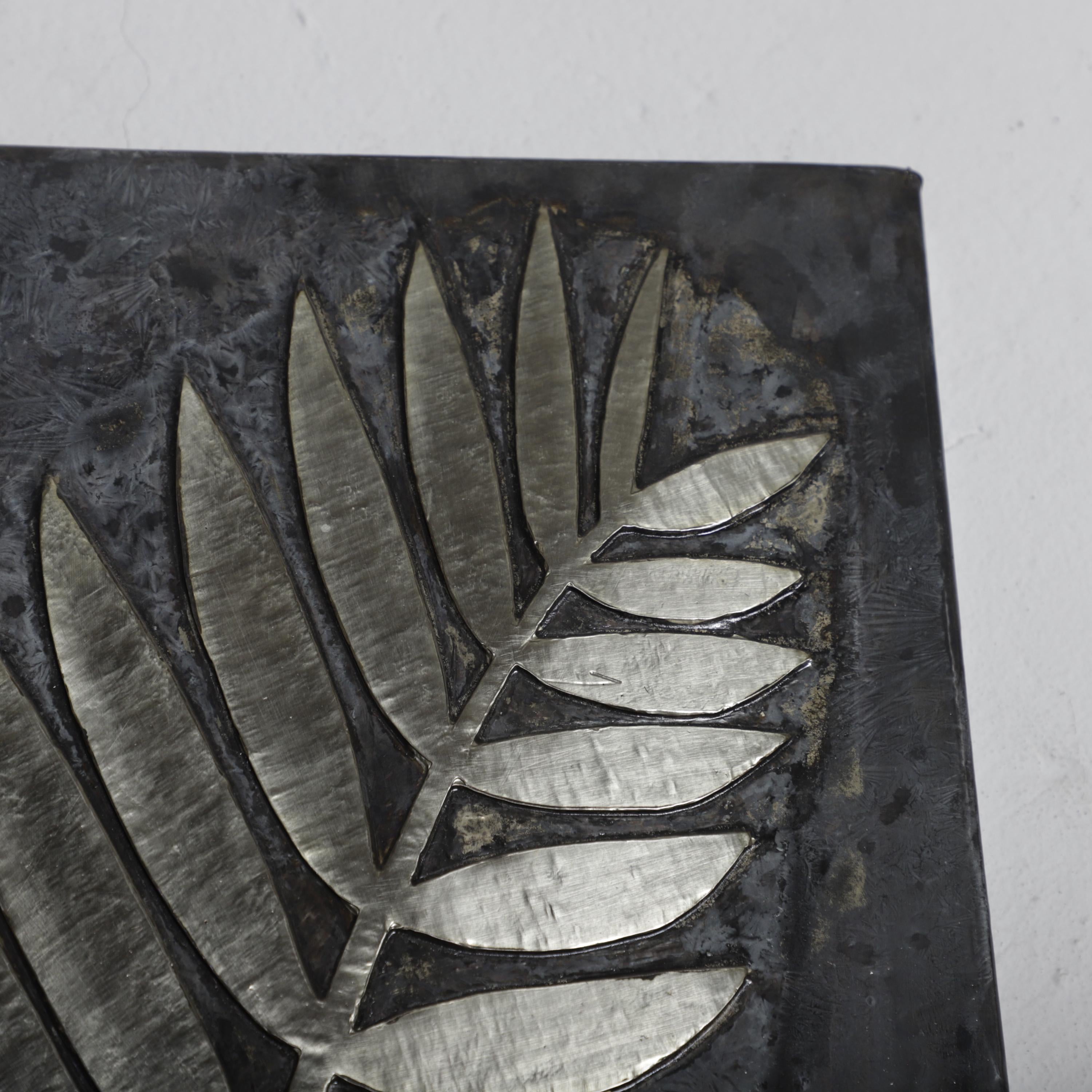 a close-up view of a metal leaf-like design on a dark surface.