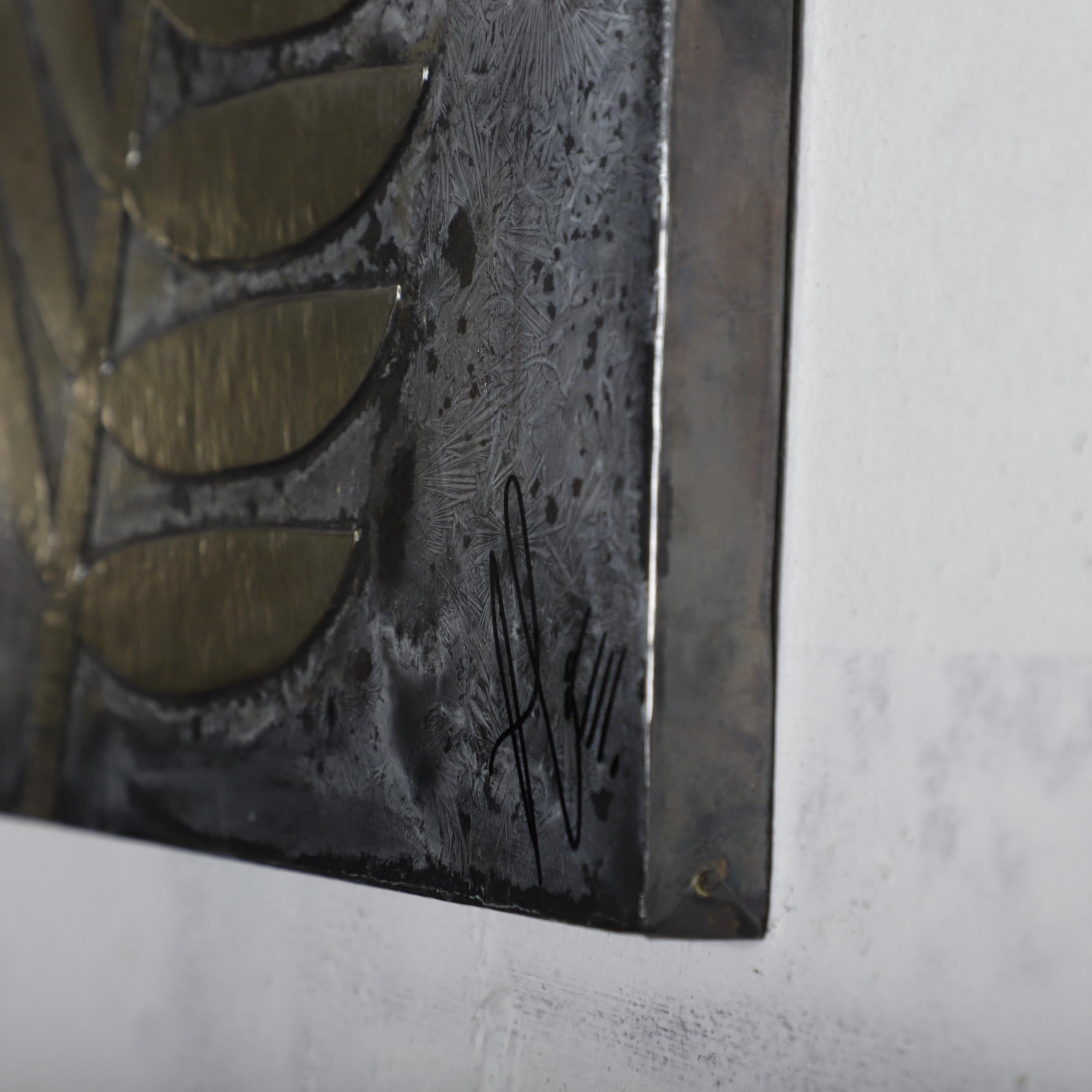 a close-up view of a metal surface with a signature or mark in the bottom right corner.