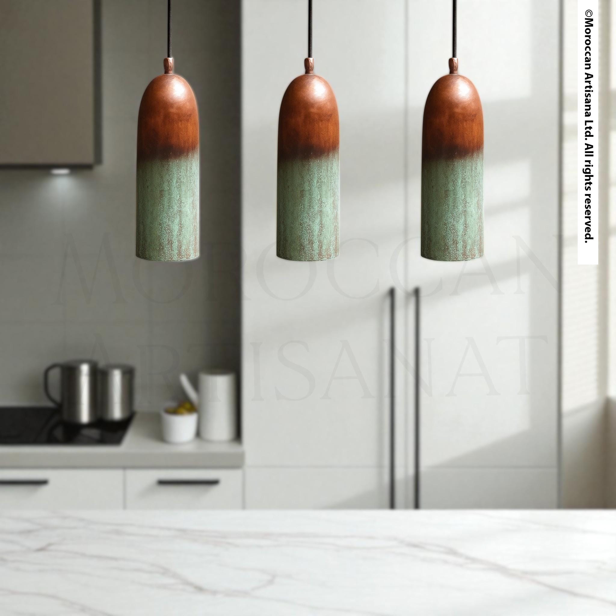 a modern kitchen with three pendant lights hanging above a marble countertop.