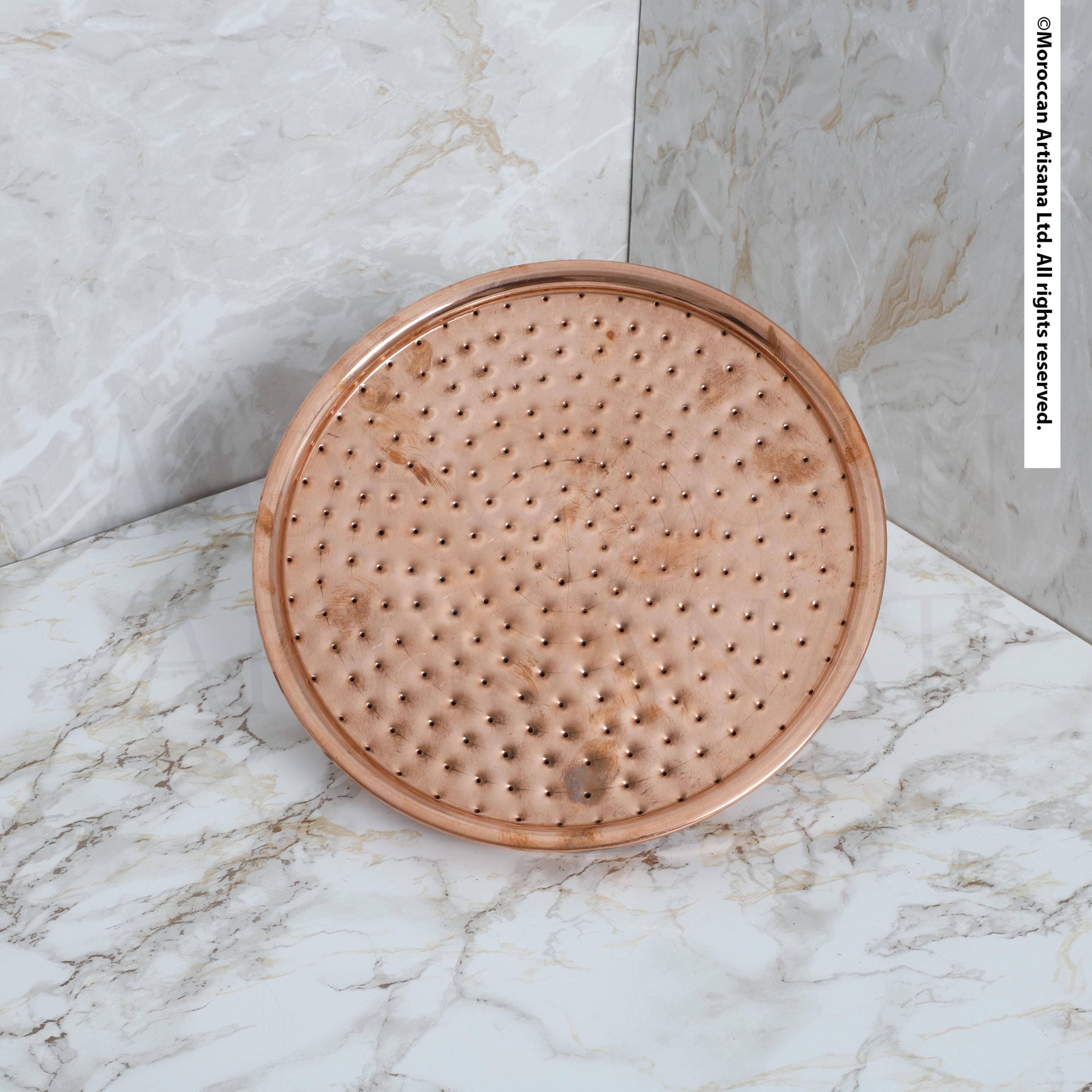 a round, metallic object with a textured surface, placed on a marble countertop.