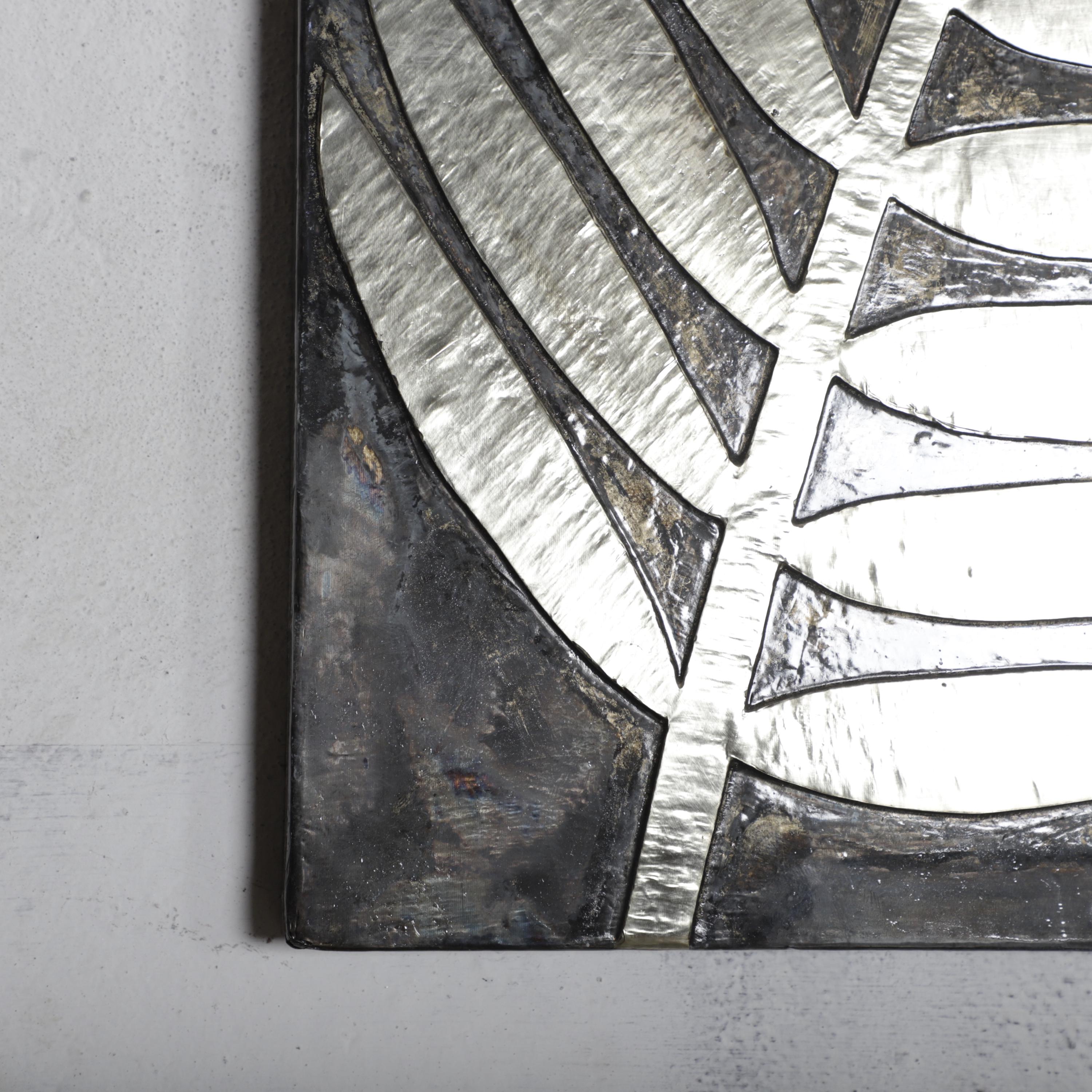 a close-up view of a metallic surface with a striking black and white pattern. The pattern consists of diagonal lines and curves, creating a visually striking contrast against the metallic background. The image does not contain any text or additional objects, and the focus is solely on the intricate design and texture of the metallic surface.