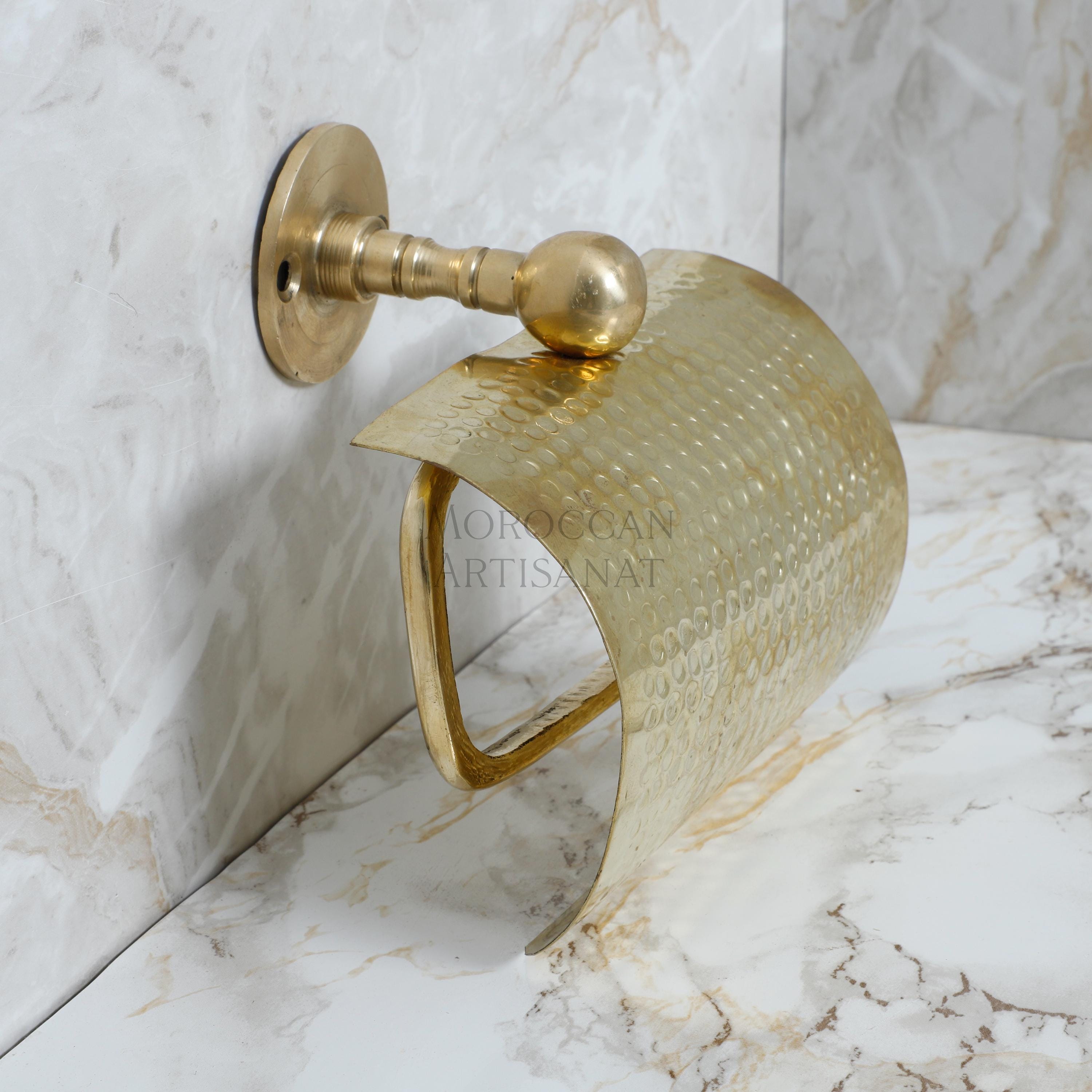 a gold toilet roll holder on a marble wall