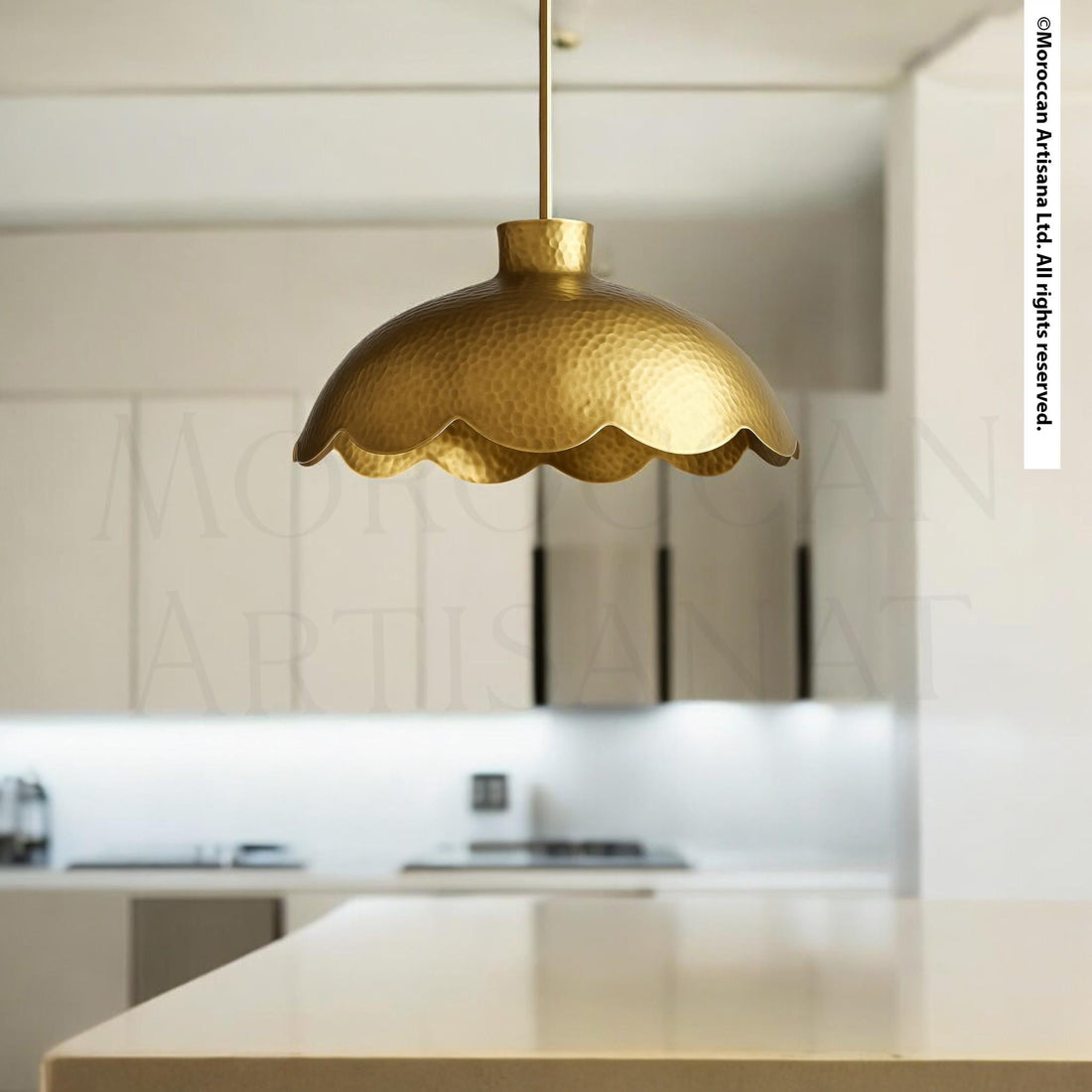 A modern kitchen with a gold-colored pendant light hanging above a white countertop.