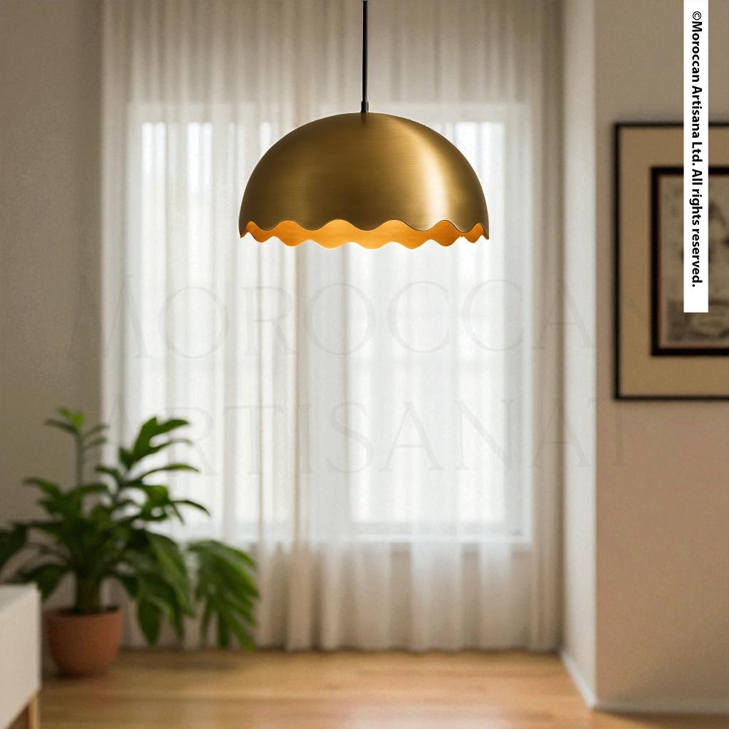 a modern, gold-colored pendant light hanging from the ceiling in a room with a large window and a plant.