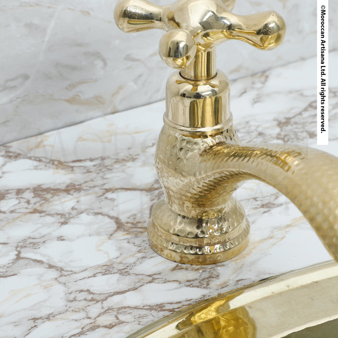 A close-up view of a gold-colored faucet with a textured surface, likely a marble countertop, against a white background.