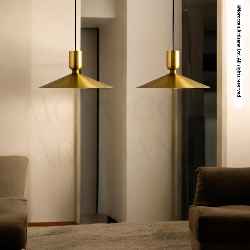 two gold pendant lights hanging from the ceiling in a modern living room setting.