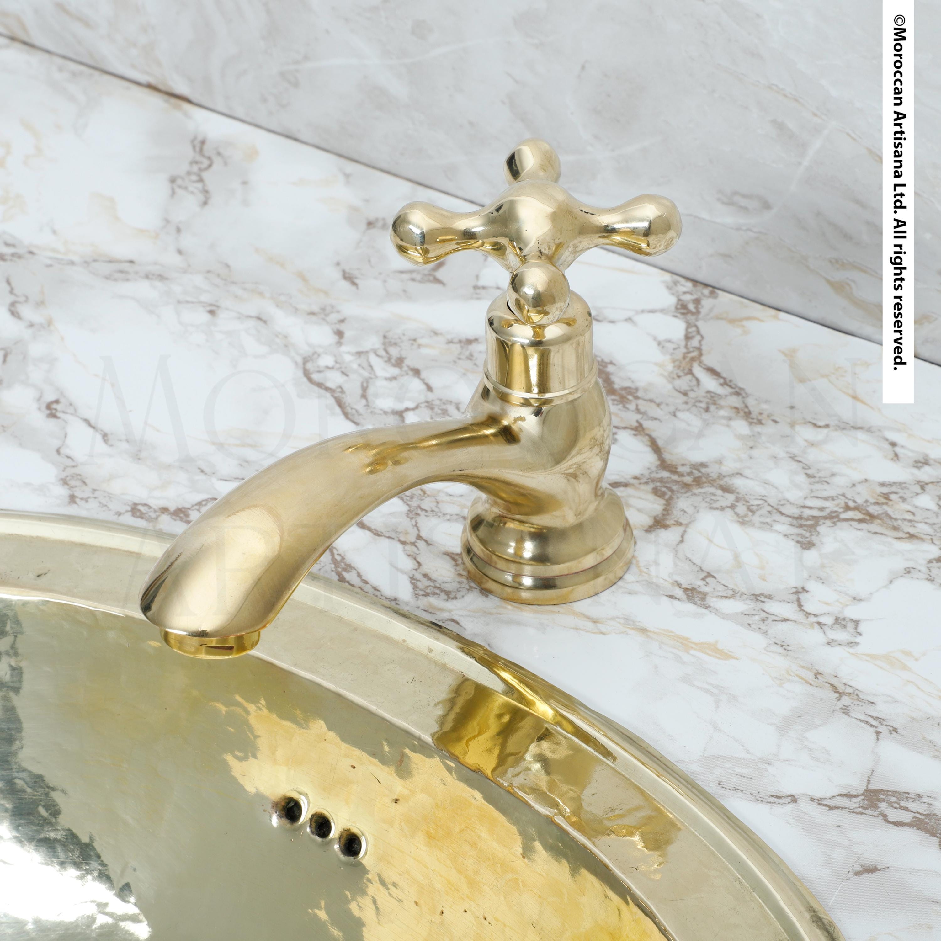 A gold-colored bathroom faucet is attached to a marble countertop.