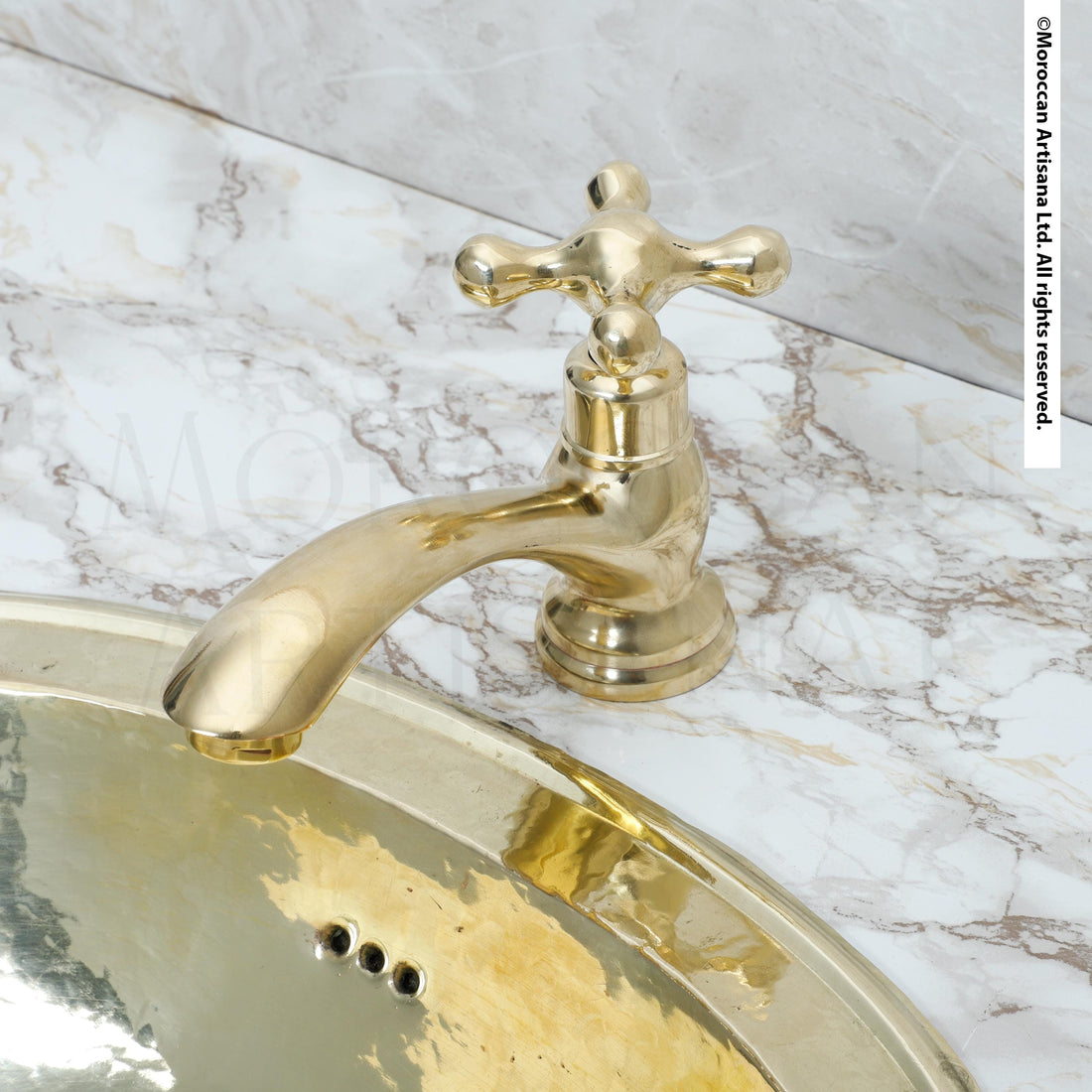 A gold-colored bathroom faucet is attached to a marble countertop.