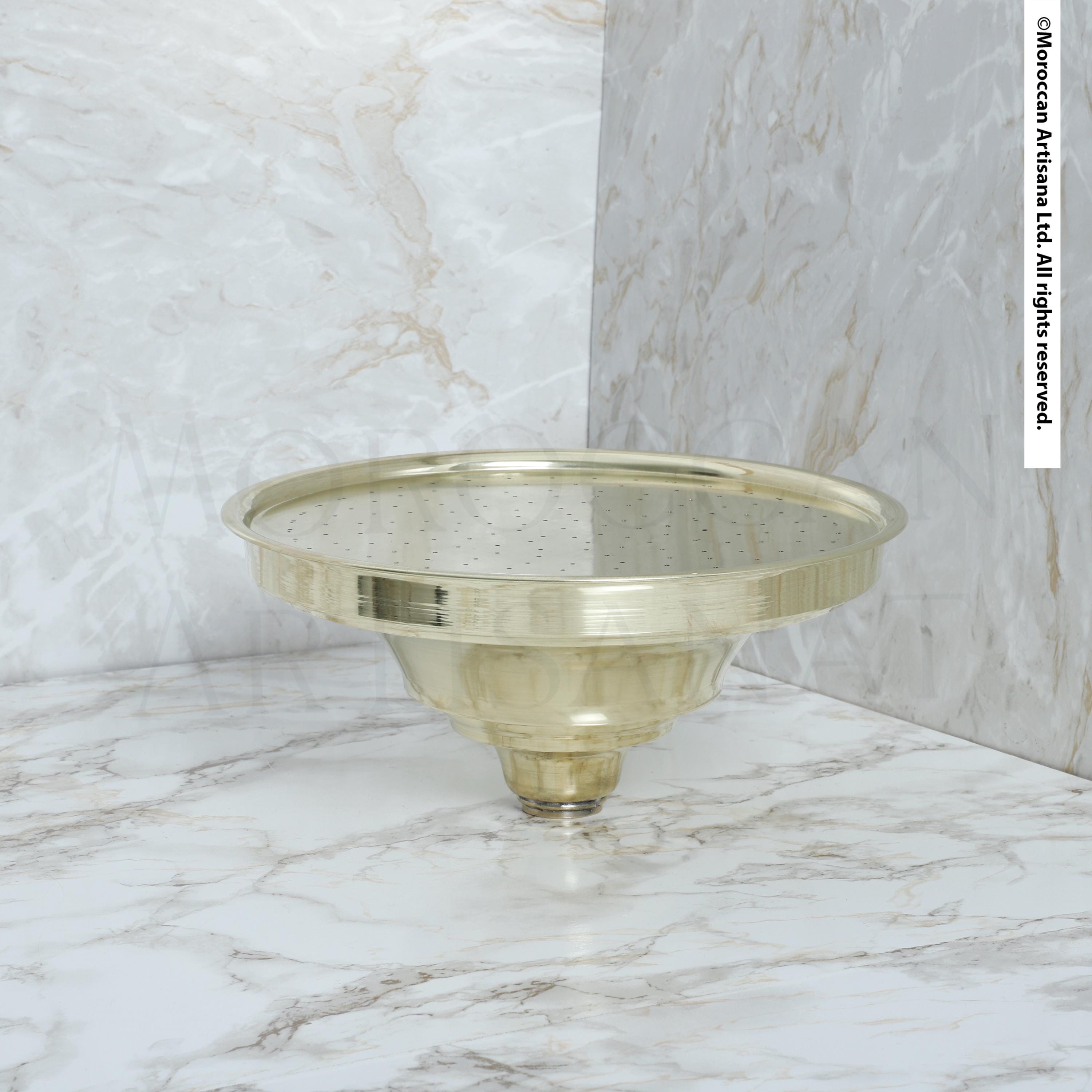 a round brass object with a reflective surface, placed on a marble countertop.