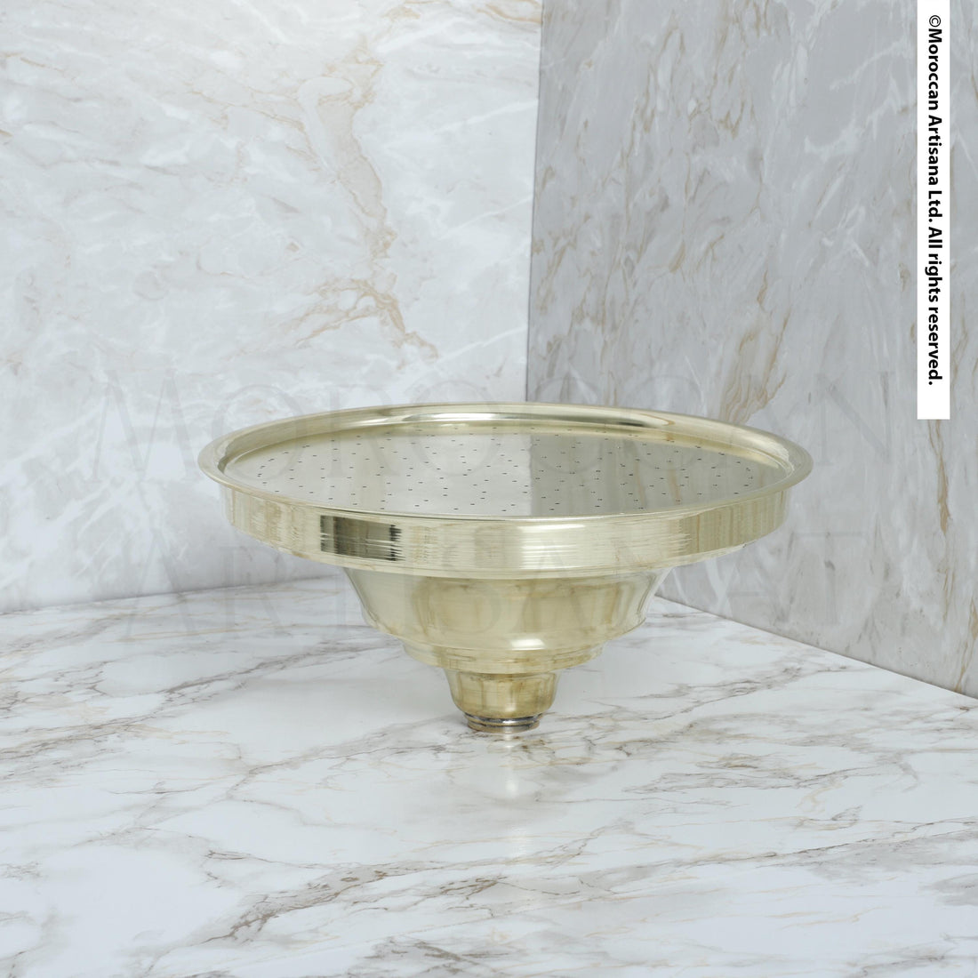 a round brass object with a reflective surface, placed on a marble countertop.