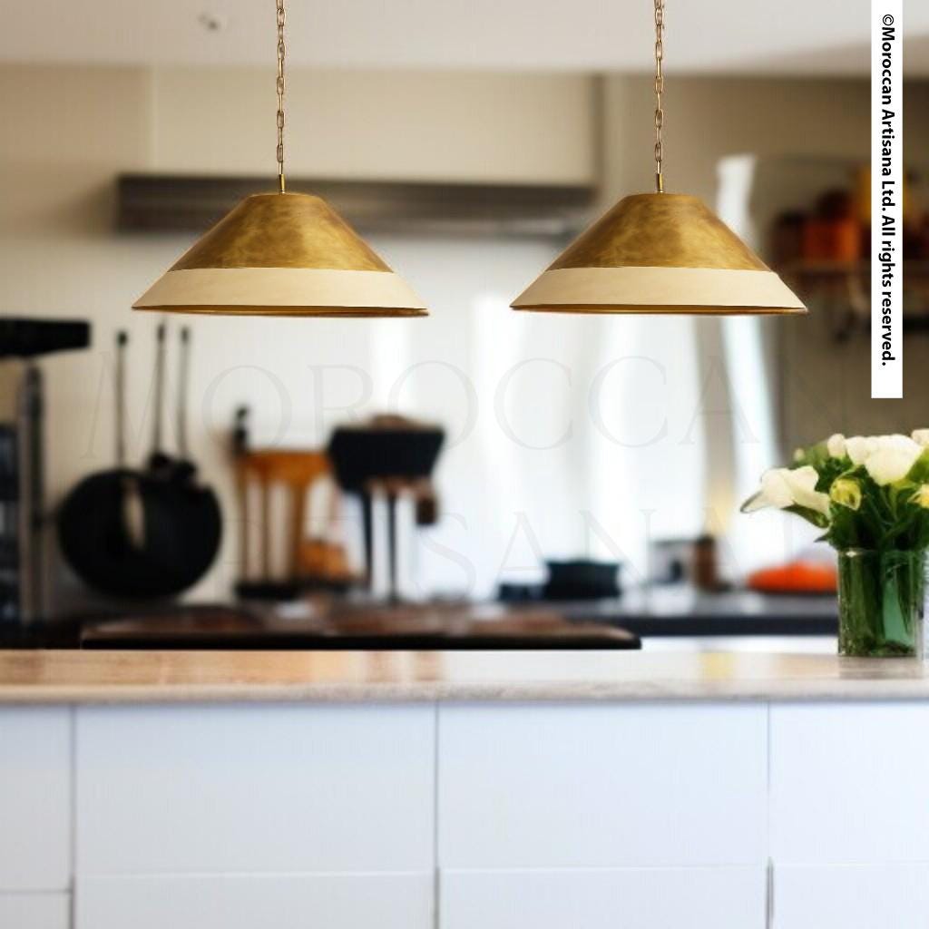a kitchen with two hanging pendant lights, a vase of flowers on the counter, and various kitchen appliances and utensils in the background.