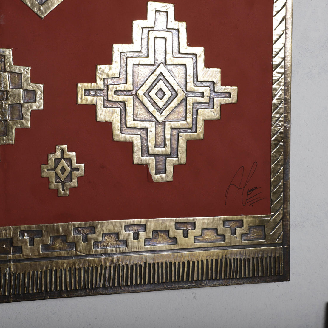 a close-up view of a decorative metal piece with a geometric pattern on a red background.