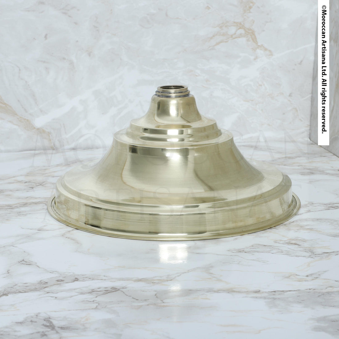 A shiny, metallic light fixture is placed on a marble surface.
