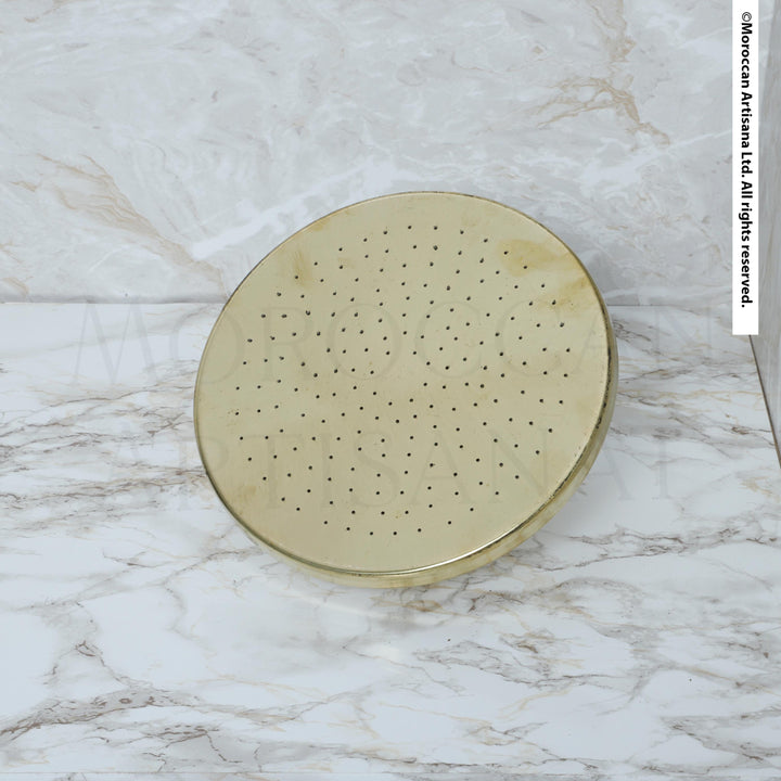 a round, metallic object with a perforated surface, placed on a marble countertop.