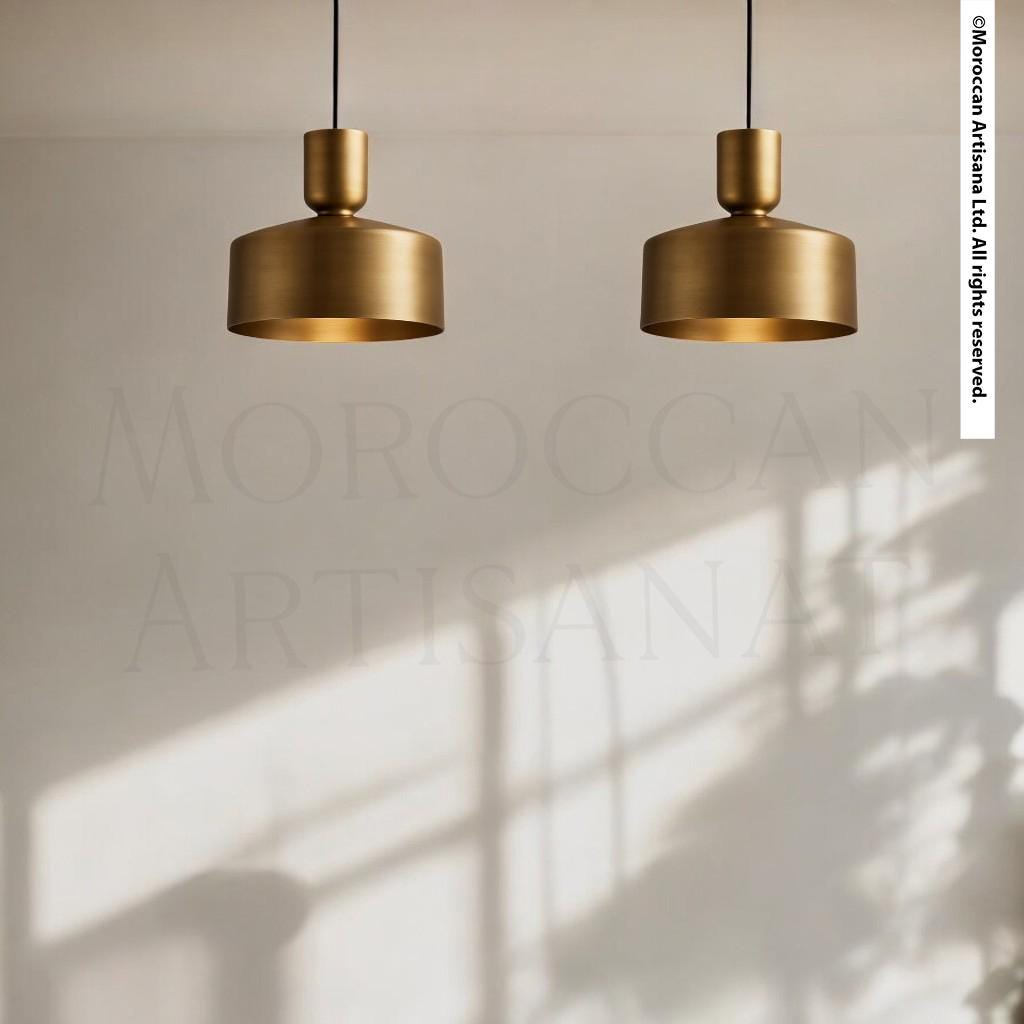 two gold-colored pendant lights hanging from the ceiling, casting a shadow on the wall below.
