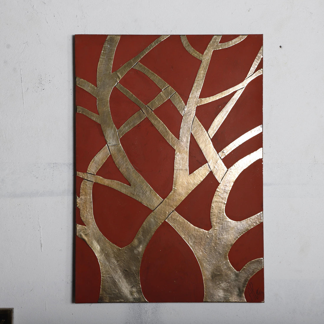 The image is a rectangular abstract artwork with a red background and a pattern of intersecting lines and shapes in gold and silver.