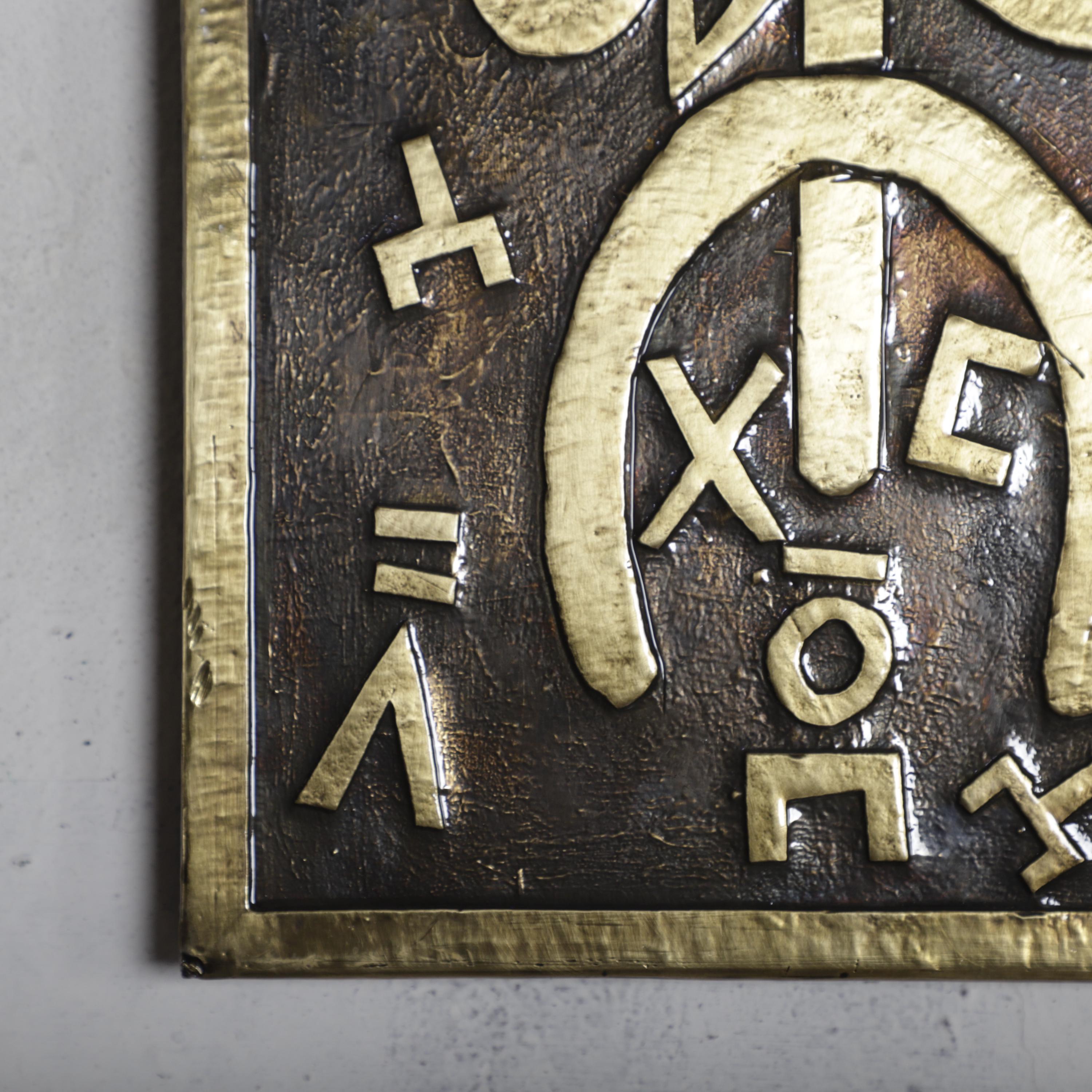 a close-up view of a metal plaque with various symbols and text engraved on it.