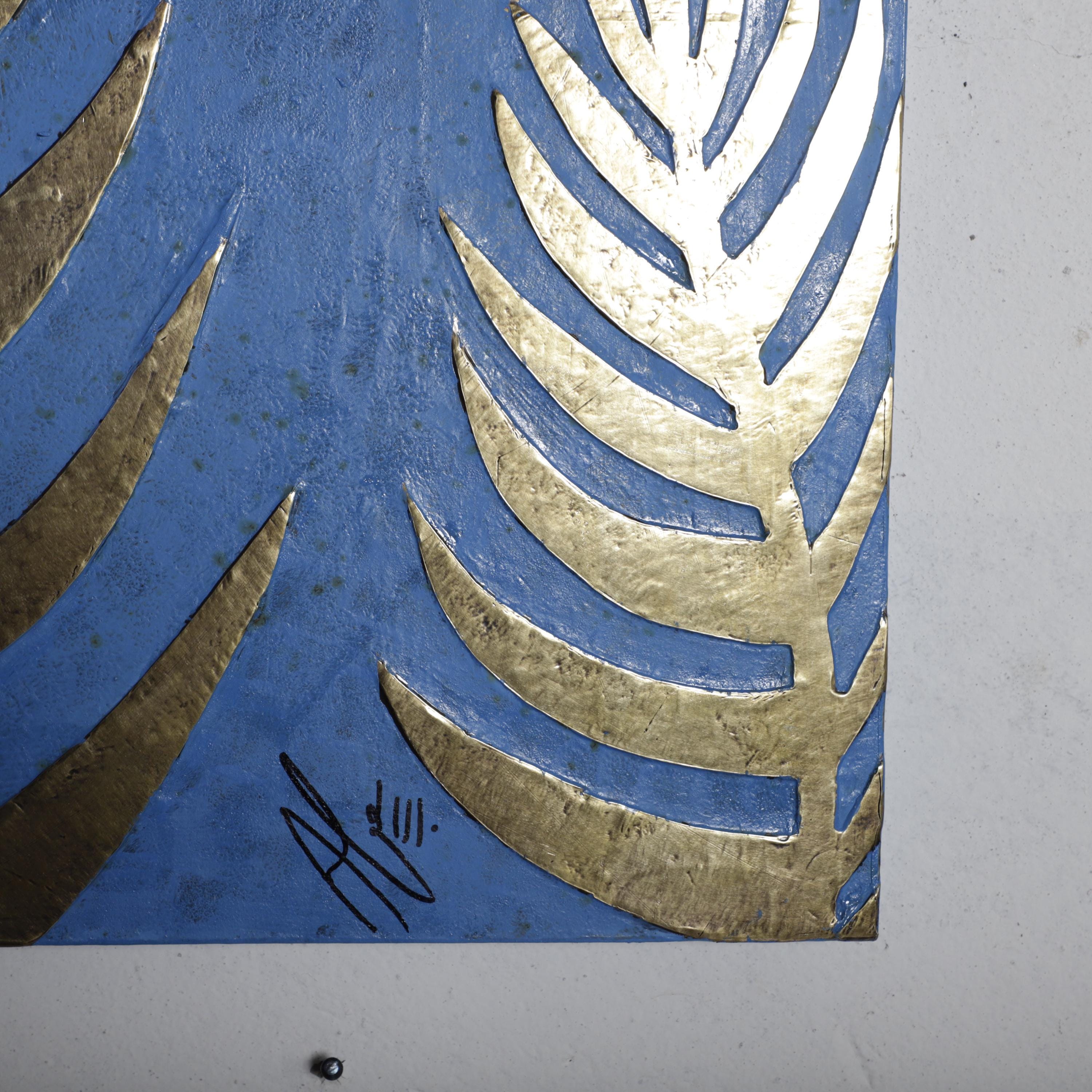 a close-up view of a blue and gold leaf-like pattern on a surface, with a signature in the bottom left corner.