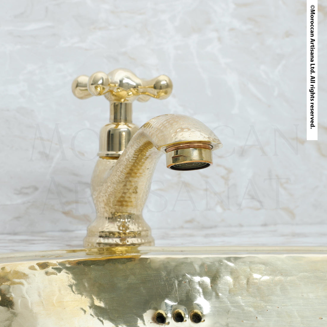 A close-up image of a gold-colored faucet with a textured finish, set against a marble background.
