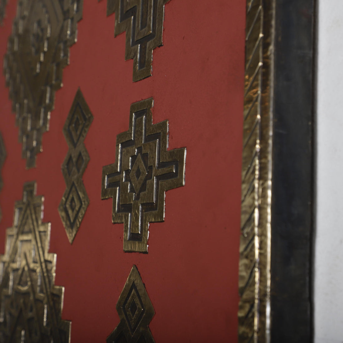 a close-up view of a red wall with intricate geometric patterns in gold and black.
