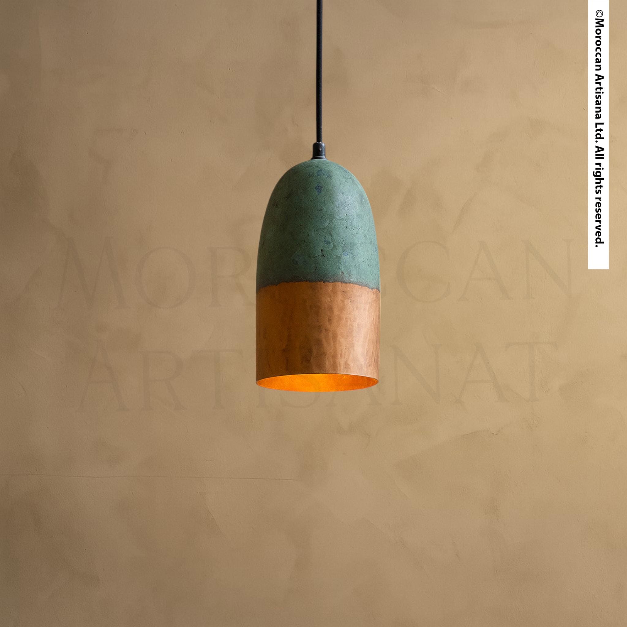 A modern pendant light with a green and orange color scheme hangs from the ceiling against a textured beige wall.