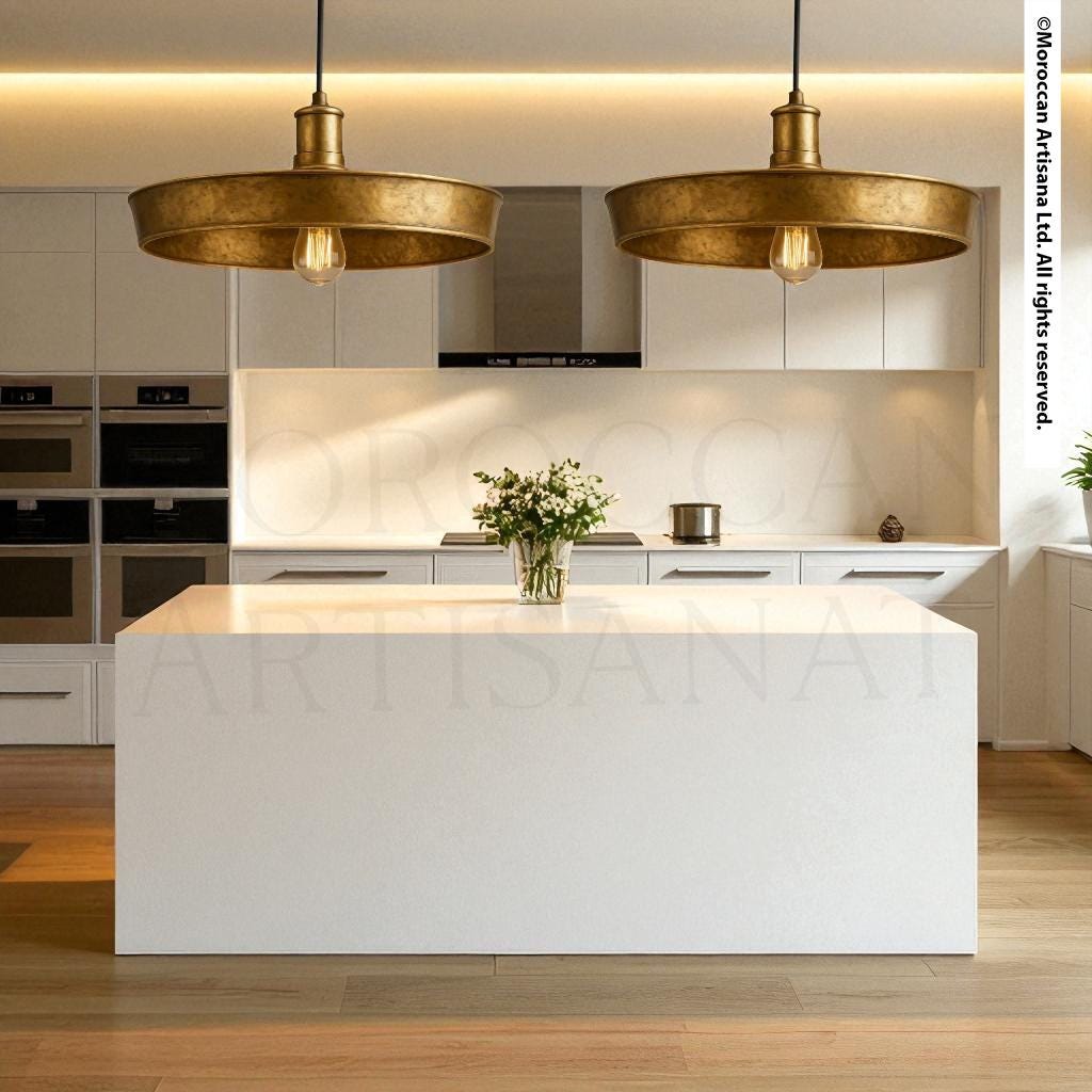 a modern, minimalist kitchen with a large white island, two pendant lights, and a vase of flowers on the island.