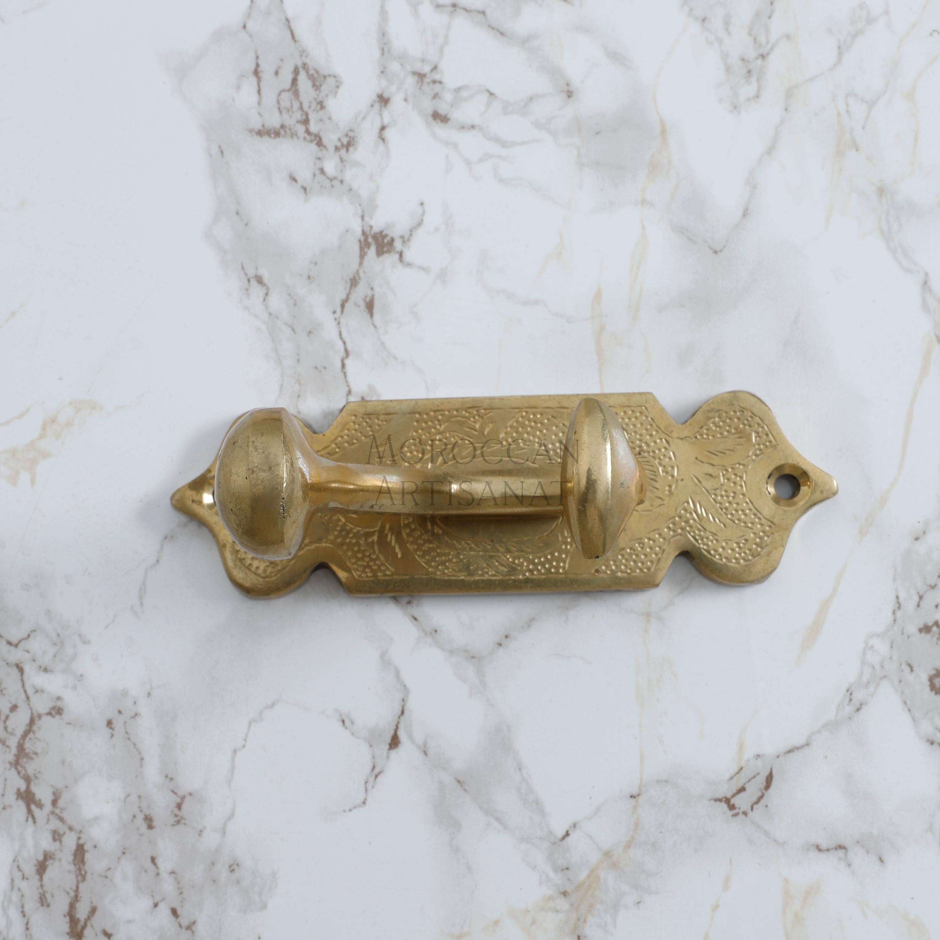 a golden door handle on a marble wall