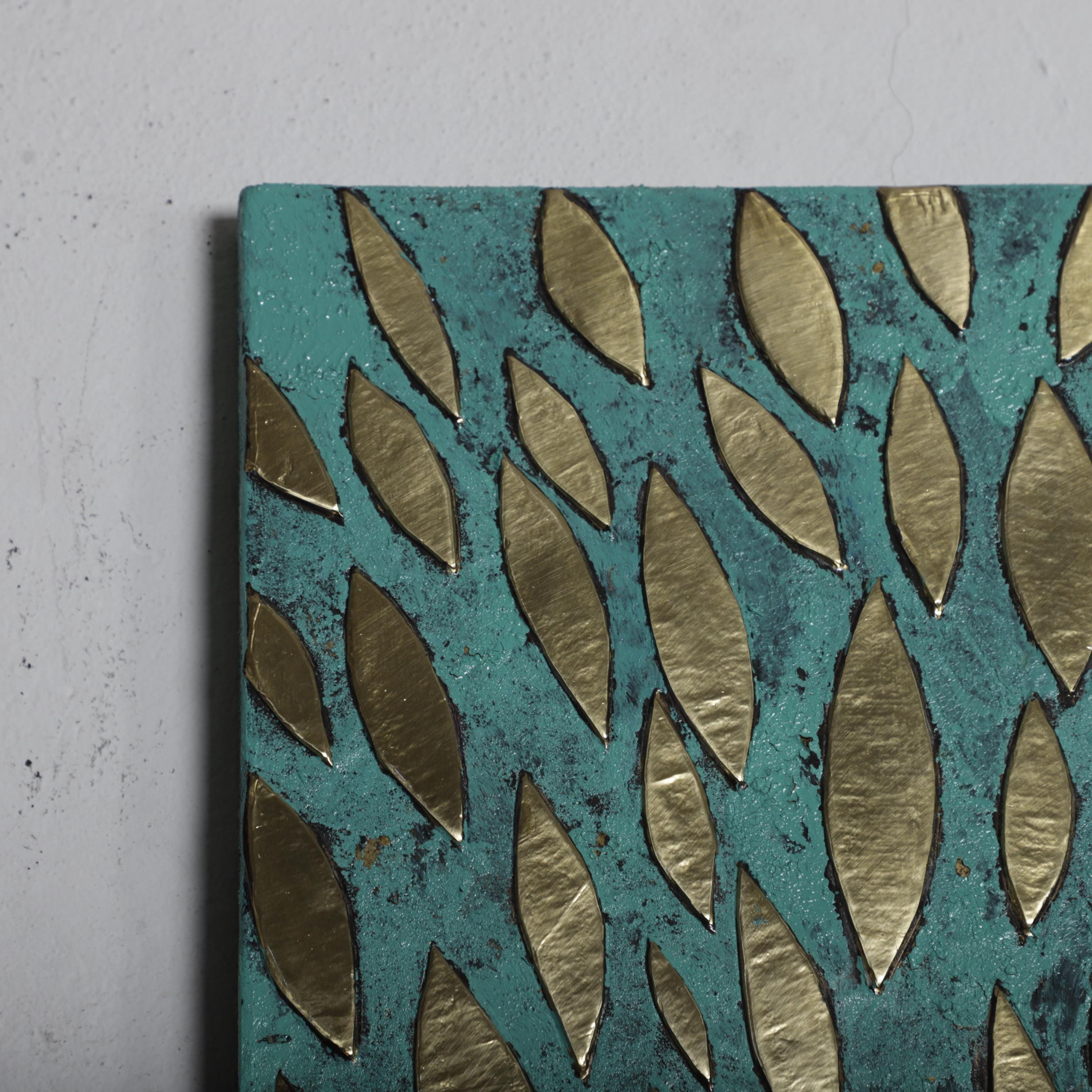 a close-up view of a piece of art with a textured background in shades of green and blue, adorned with gold leaf-like shapes.