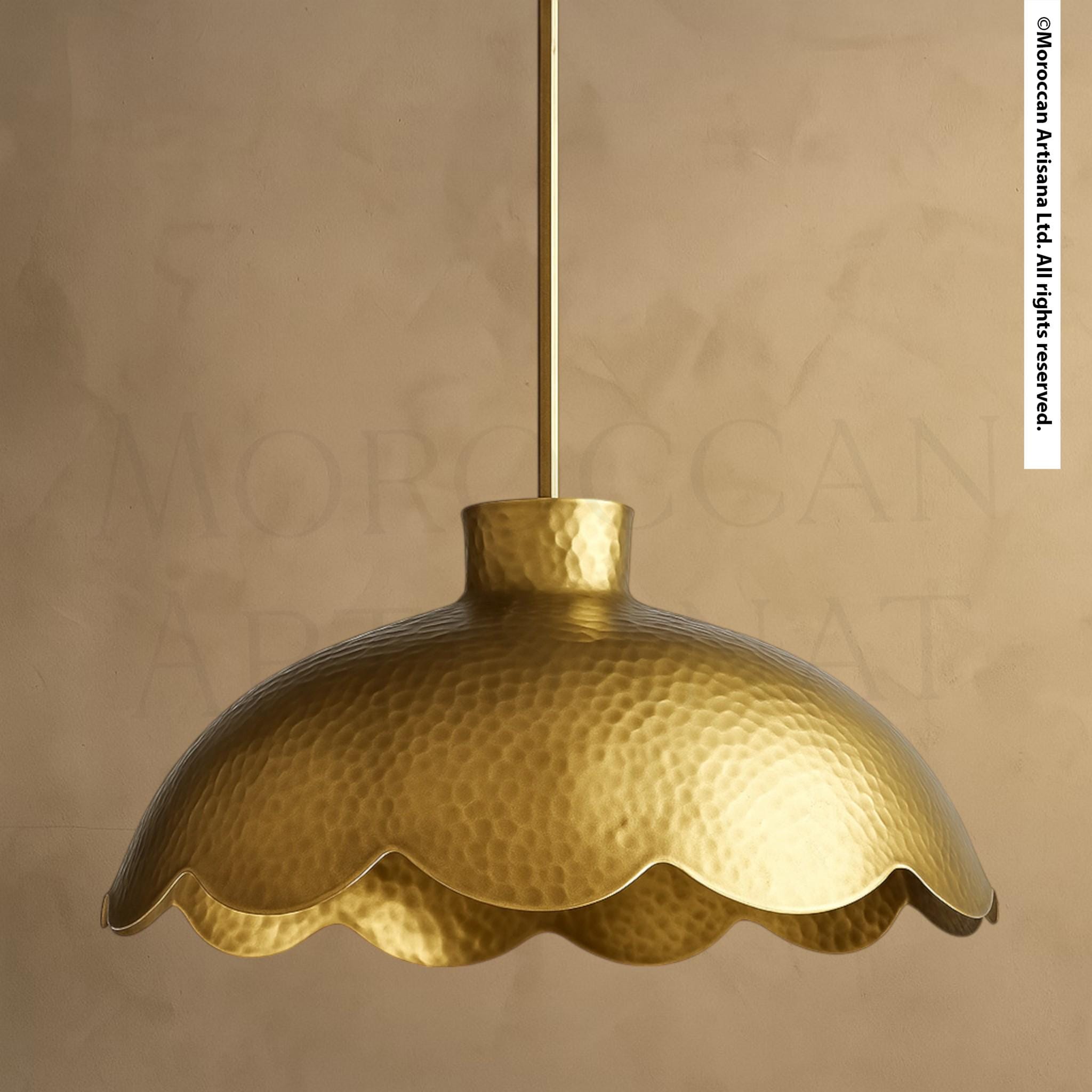A gold-colored pendant light fixture with a scalloped edge hangs from a hook against a beige background.