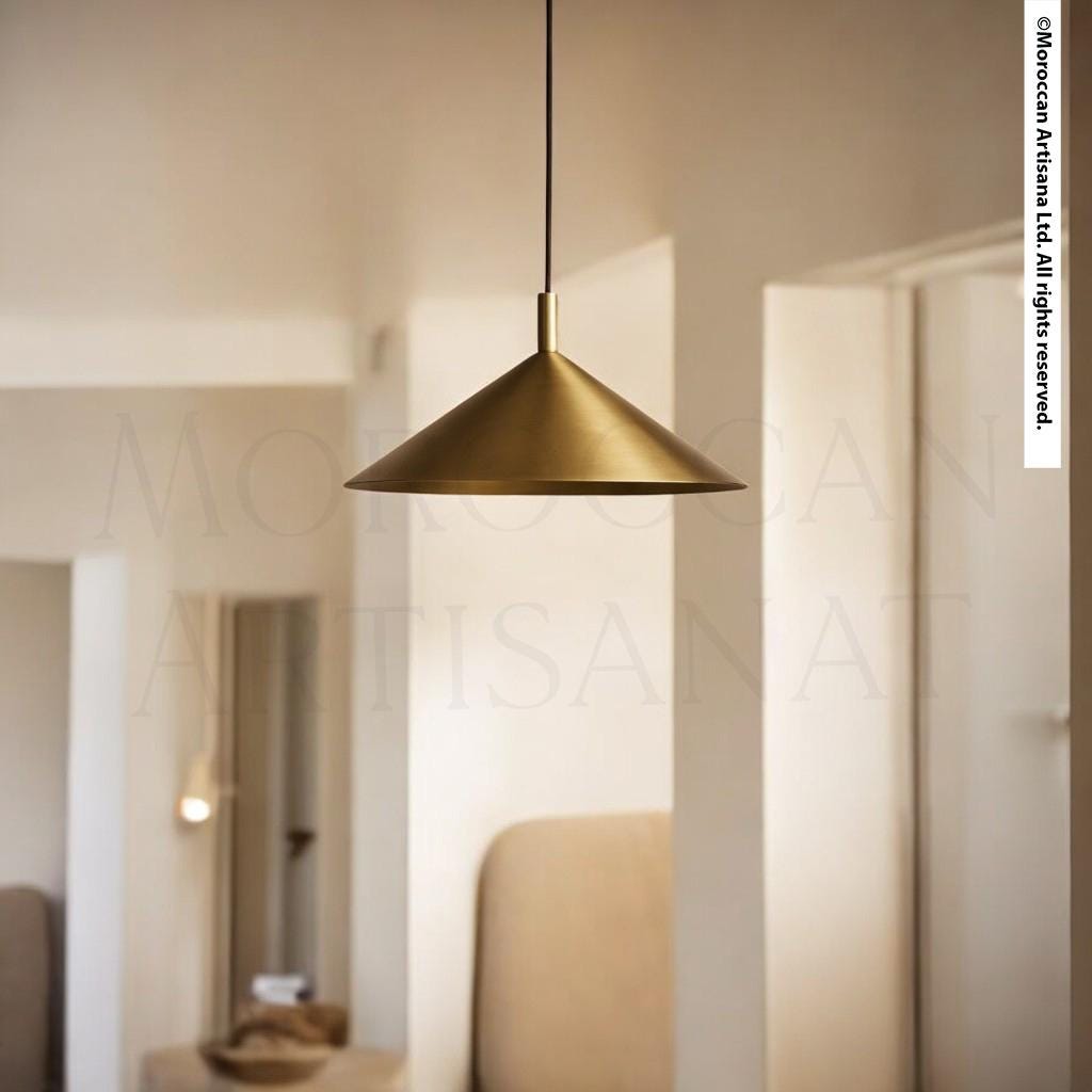 A gold pendant lamp hangs from the ceiling in a minimalist, white-themed room.