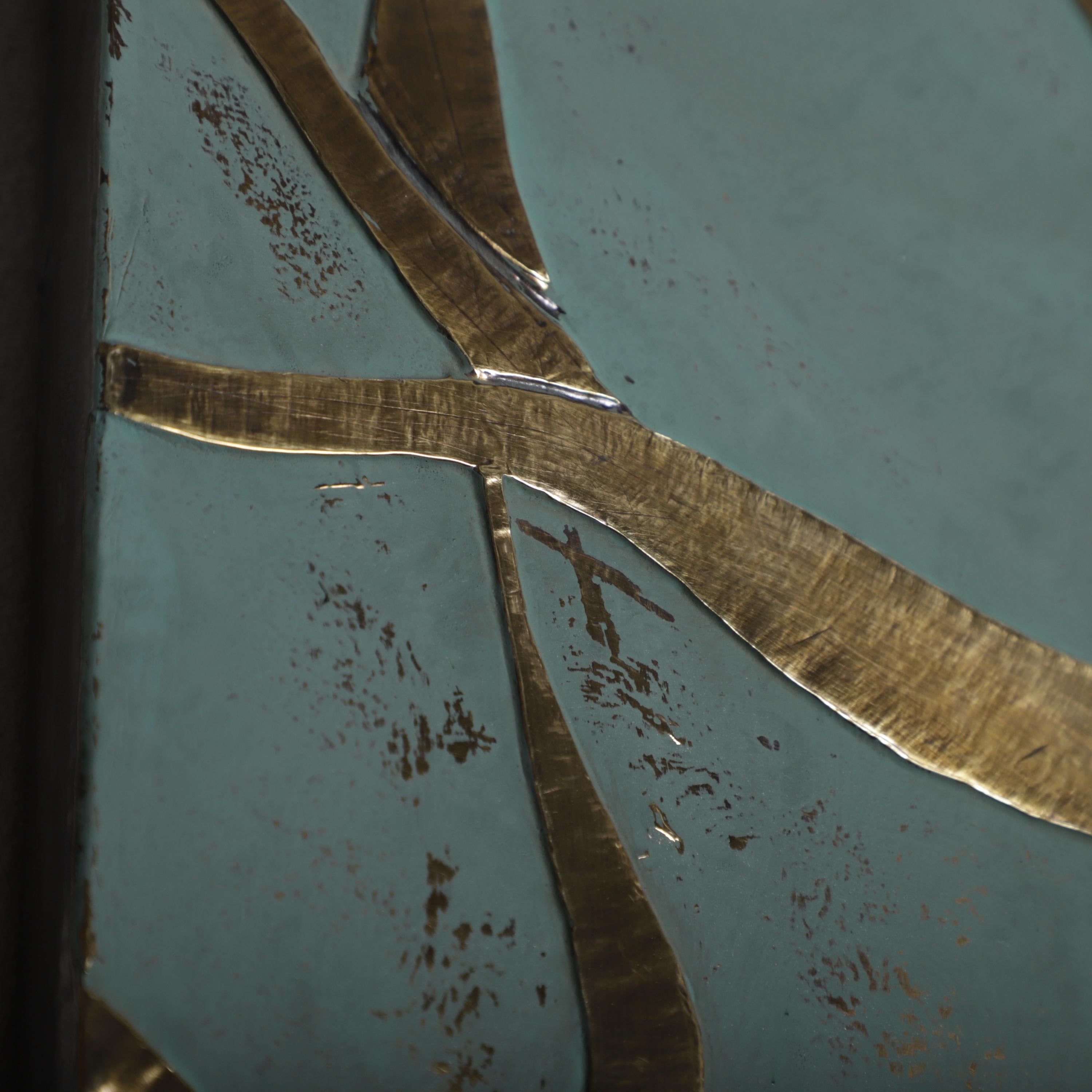 a close-up view of a textured surface with a metallic, gold-colored design. The design appears to be a combination of lines and shapes, creating a visually striking and intricate pattern.