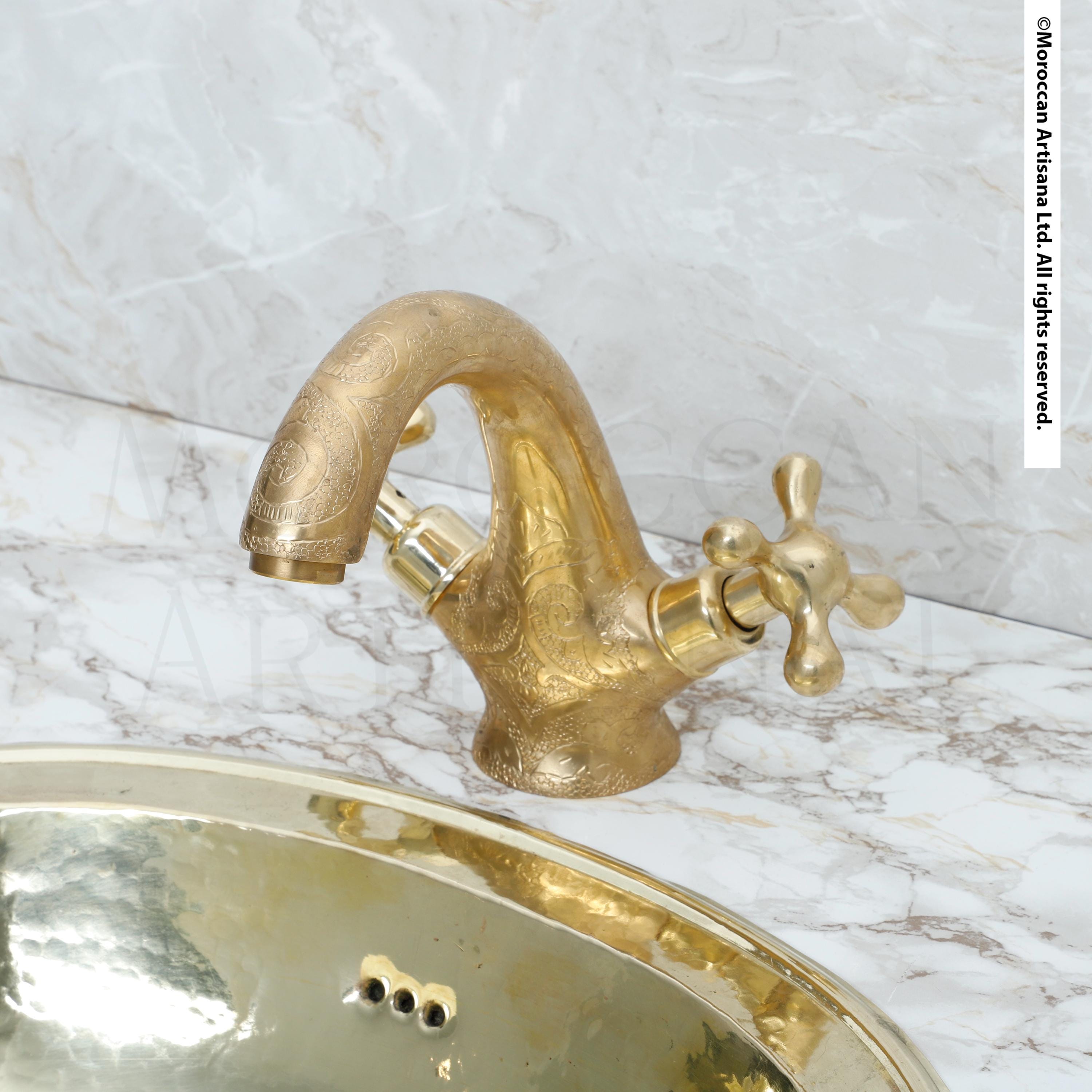 a gold-colored bathroom sink with a decorative faucet, set against a marble countertop.