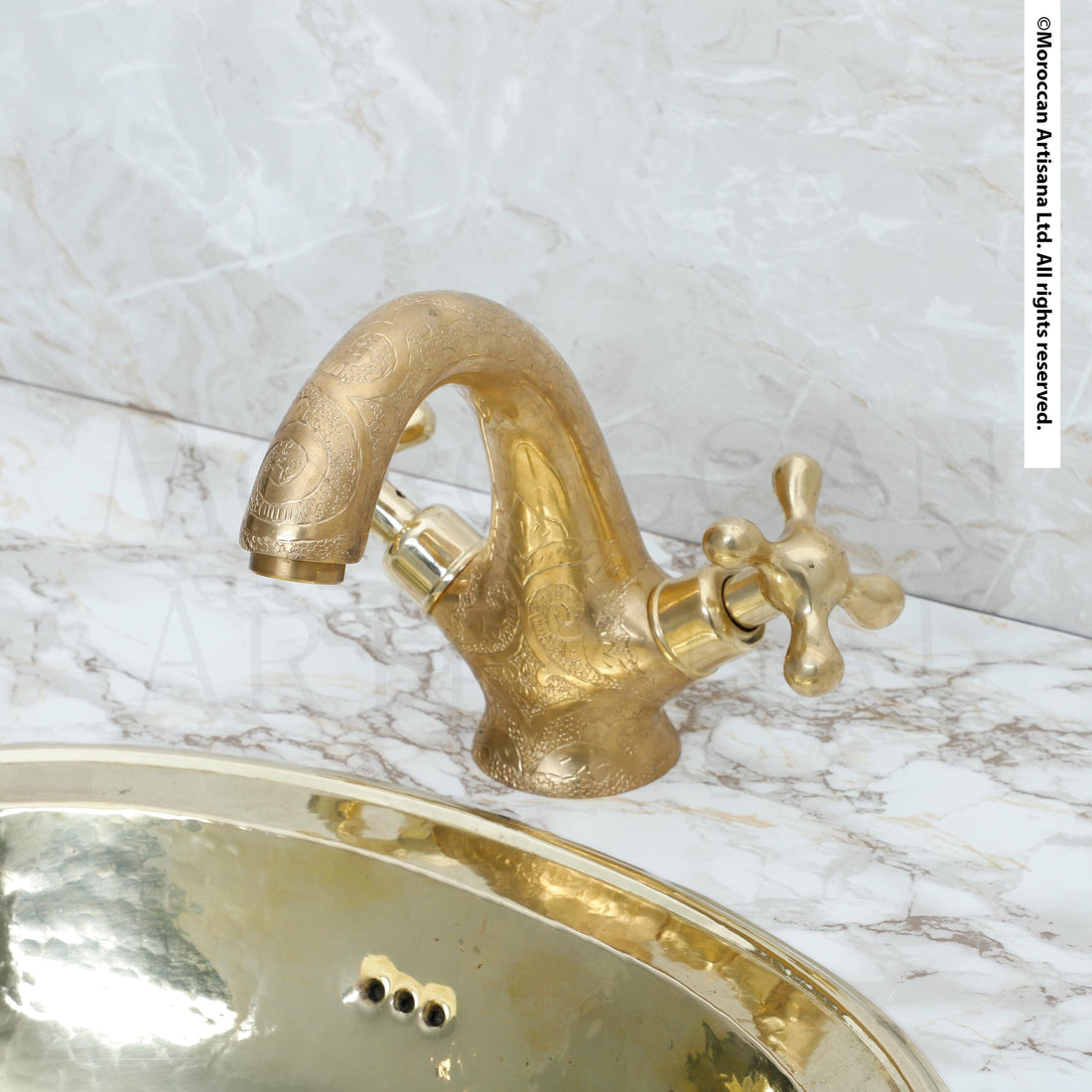 a gold-colored bathroom sink with a decorative faucet, set against a marble countertop.