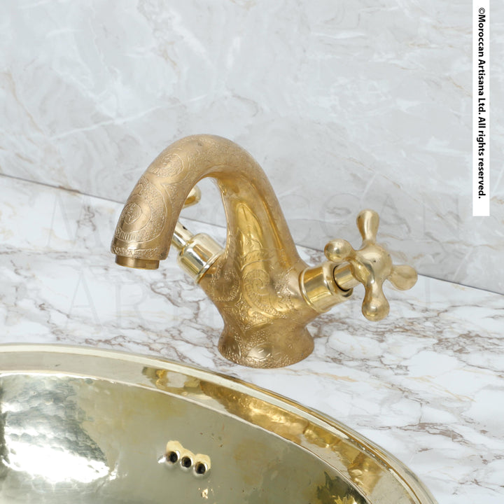 a gold-colored bathroom sink with a decorative faucet, set against a marble countertop.
