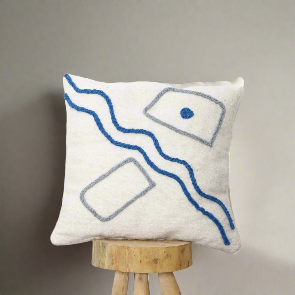 Artisan-made Moroccan pillow cover with handwoven wool, featuring neutral tones and colorful abstract designs.

