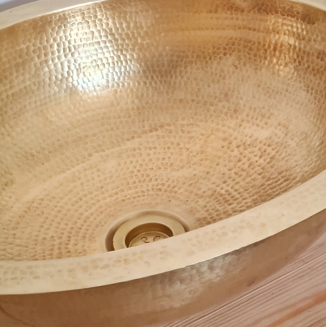 Elegant oval brass sink with a natural finish for a luxurious bathroom decor